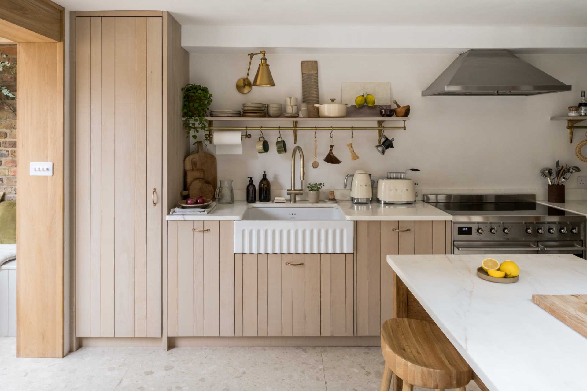 This contemporary kitchen has wood cabinets, while a white apron front sink is positioned between additional counter space and below a floating shelf.