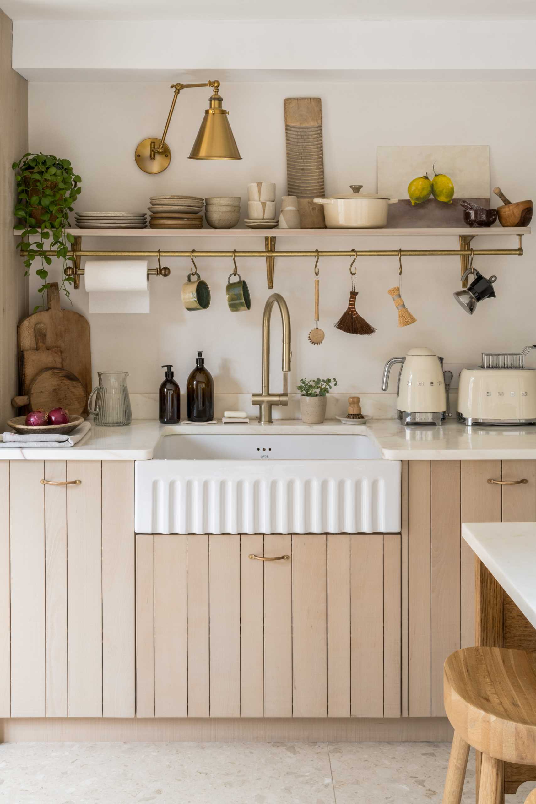 This contemporary kitchen has wood cabinets, while a white apron front sink is positioned between additional counter space and below a floating shelf.