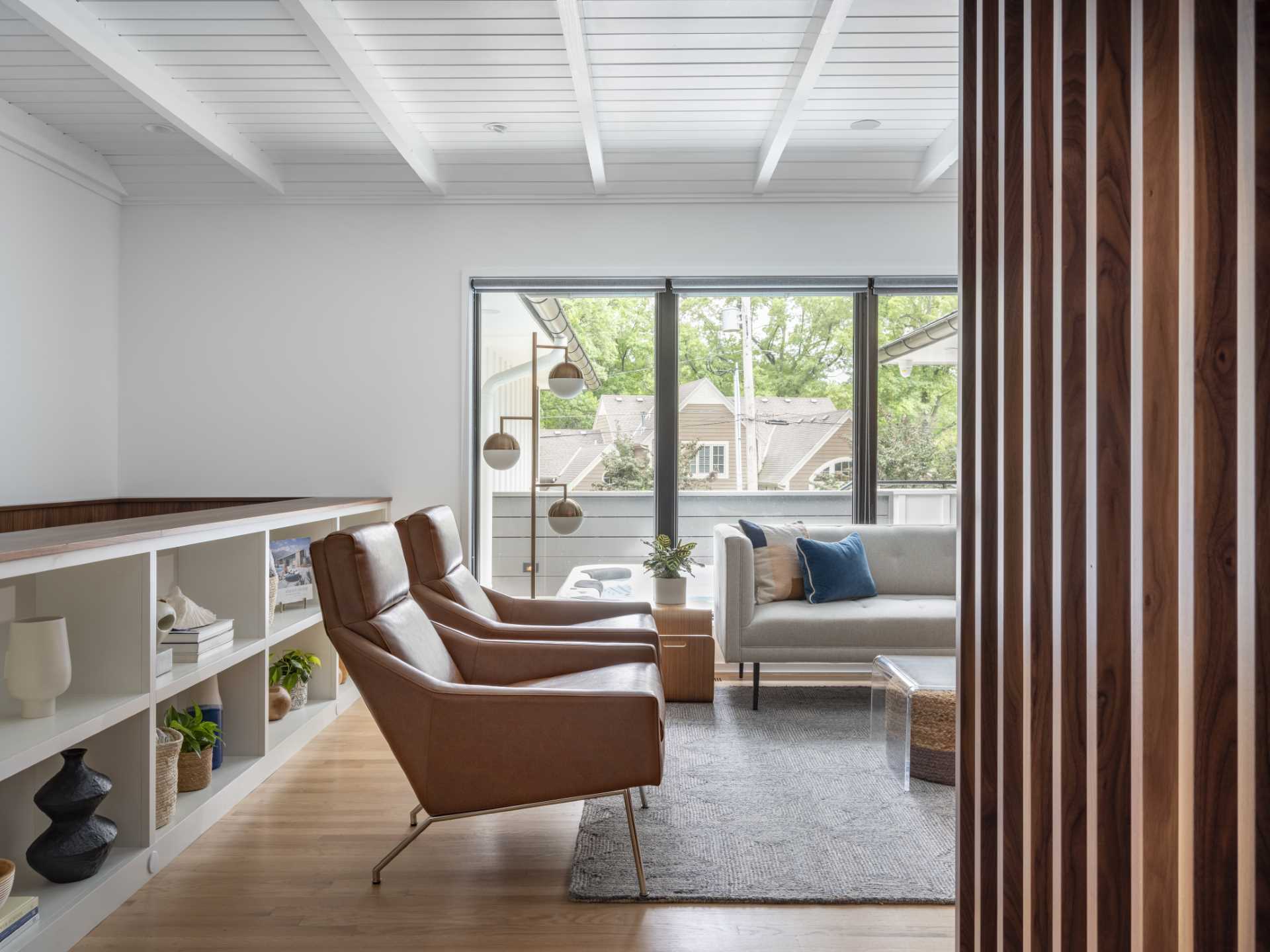 In the living room, stairs were added that lead down to a family room, while the white walls and ceiling, and the grey-painted brick fireplace reflect the colors used on the exterior of the home.