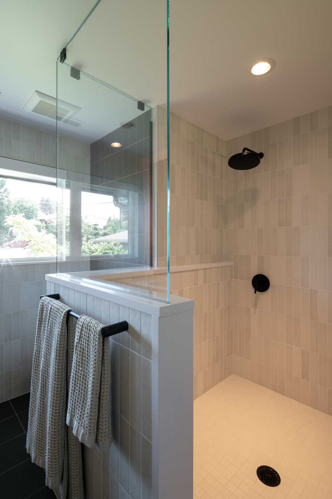 The updated primary bathroom received a changed layout, with the new double vanity located on the left wall, and the shower and toilet now located on the right. A glass shower screen allows the natural light from the window to flow through the space. Additional light has been added to the bathroom in the form of hidden LEDs behind the mirror.