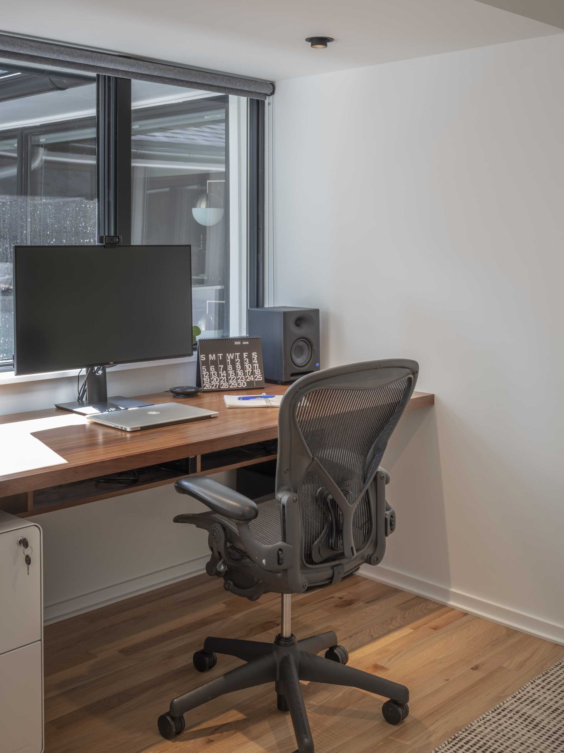 A home office is located behind a sliding door in the bedroom and includes a built-in wood desk and a wall of storage.