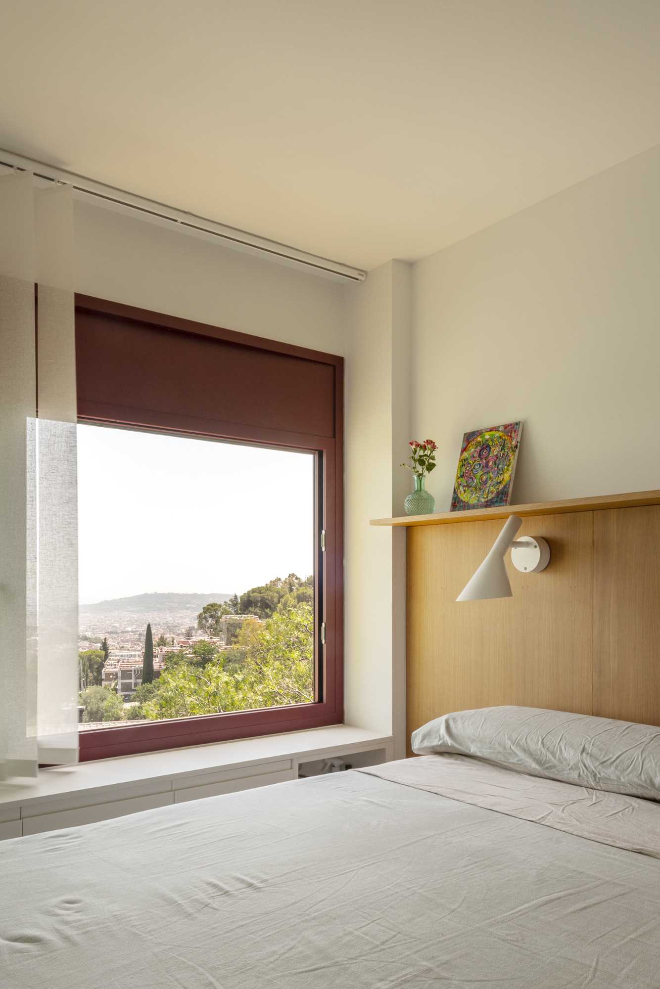 In the primary suite, a wood accent is present in the form of a headboard with a shelf, while storage has been included under the window, and an ensuite bathroom is also present.