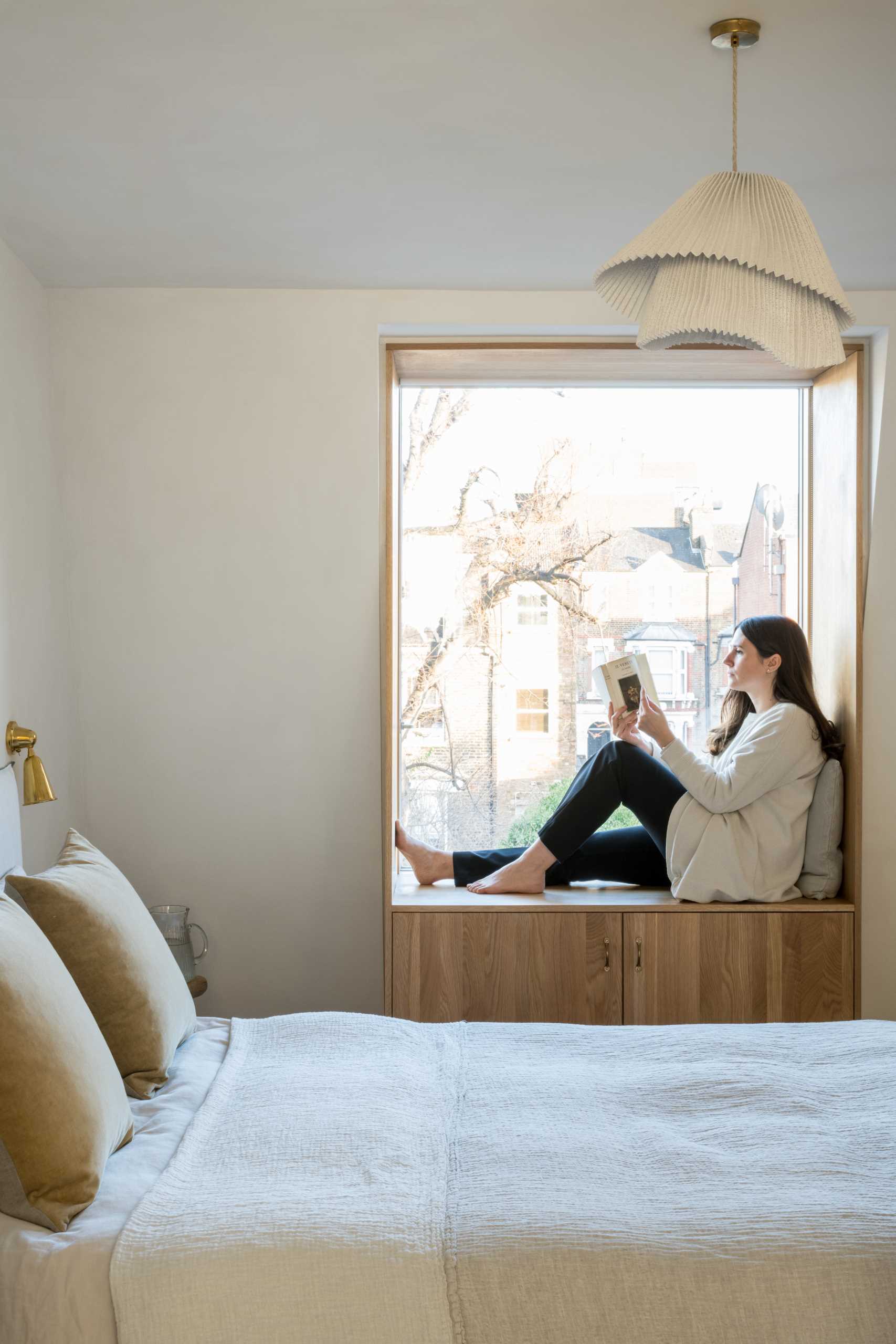 In this contemporary bedroom, there's a wood-lined window seat with storage below that overlooks the neighborhood.