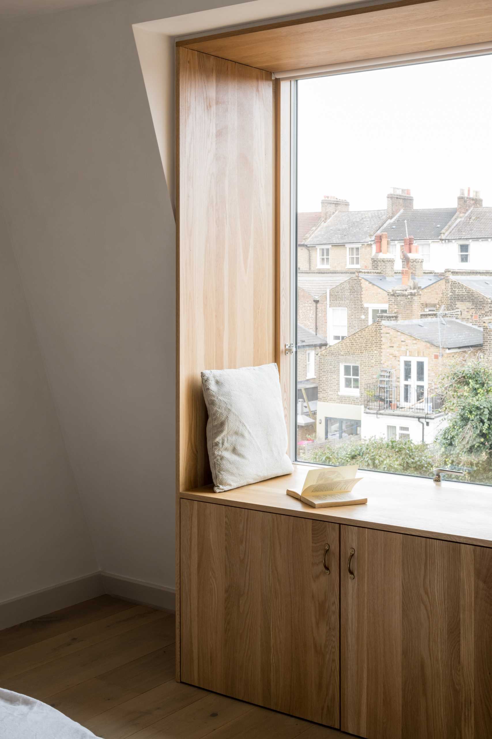 In this contemporary bedroom, there's a wood-lined window seat with storage below that overlooks the neighborhood.