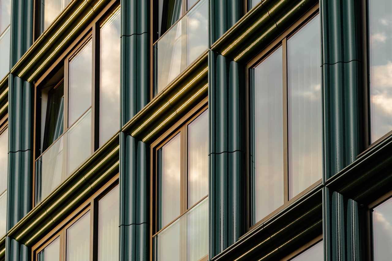 A modern building facade with glass and blue-green ceramic details.