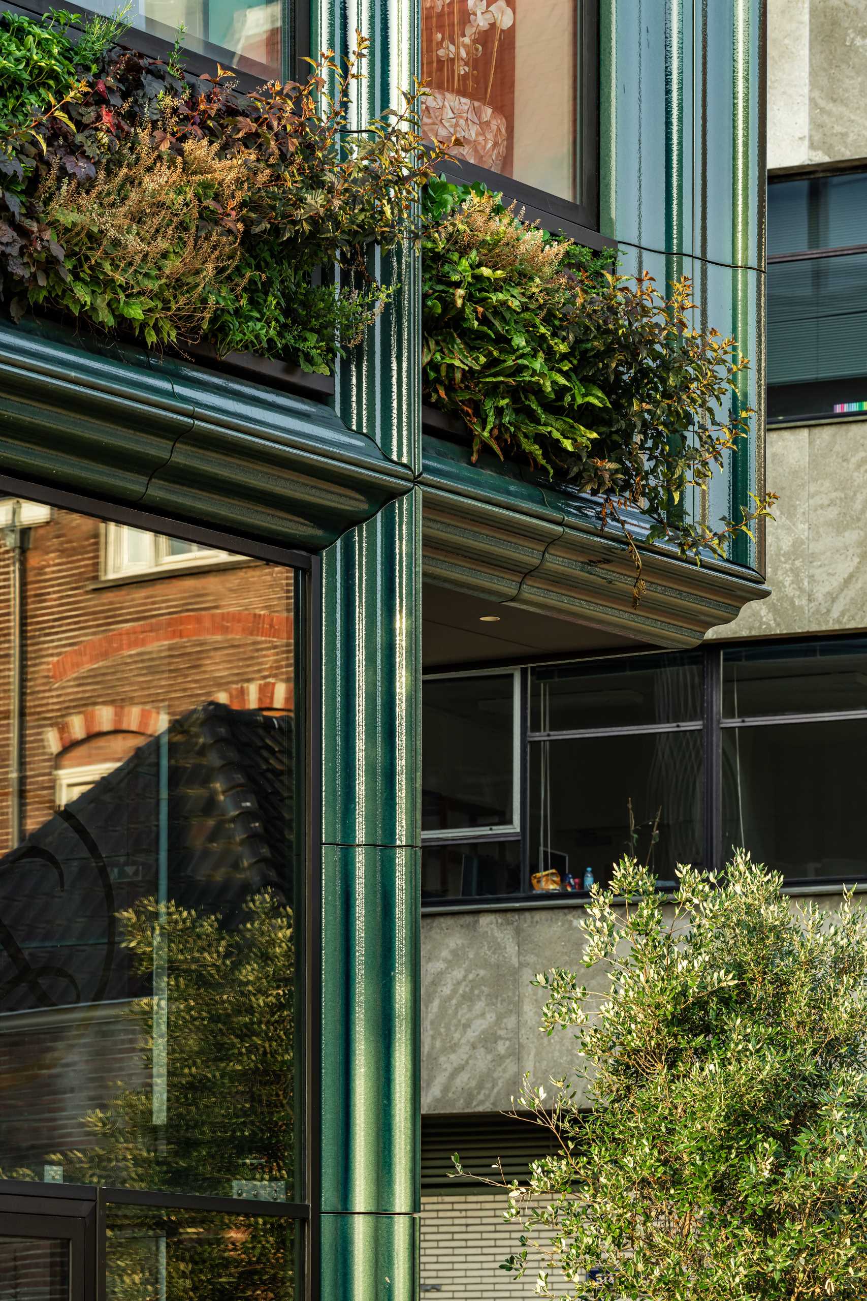 A modern building facade with glass, green walls, and blue-green ceramic details.