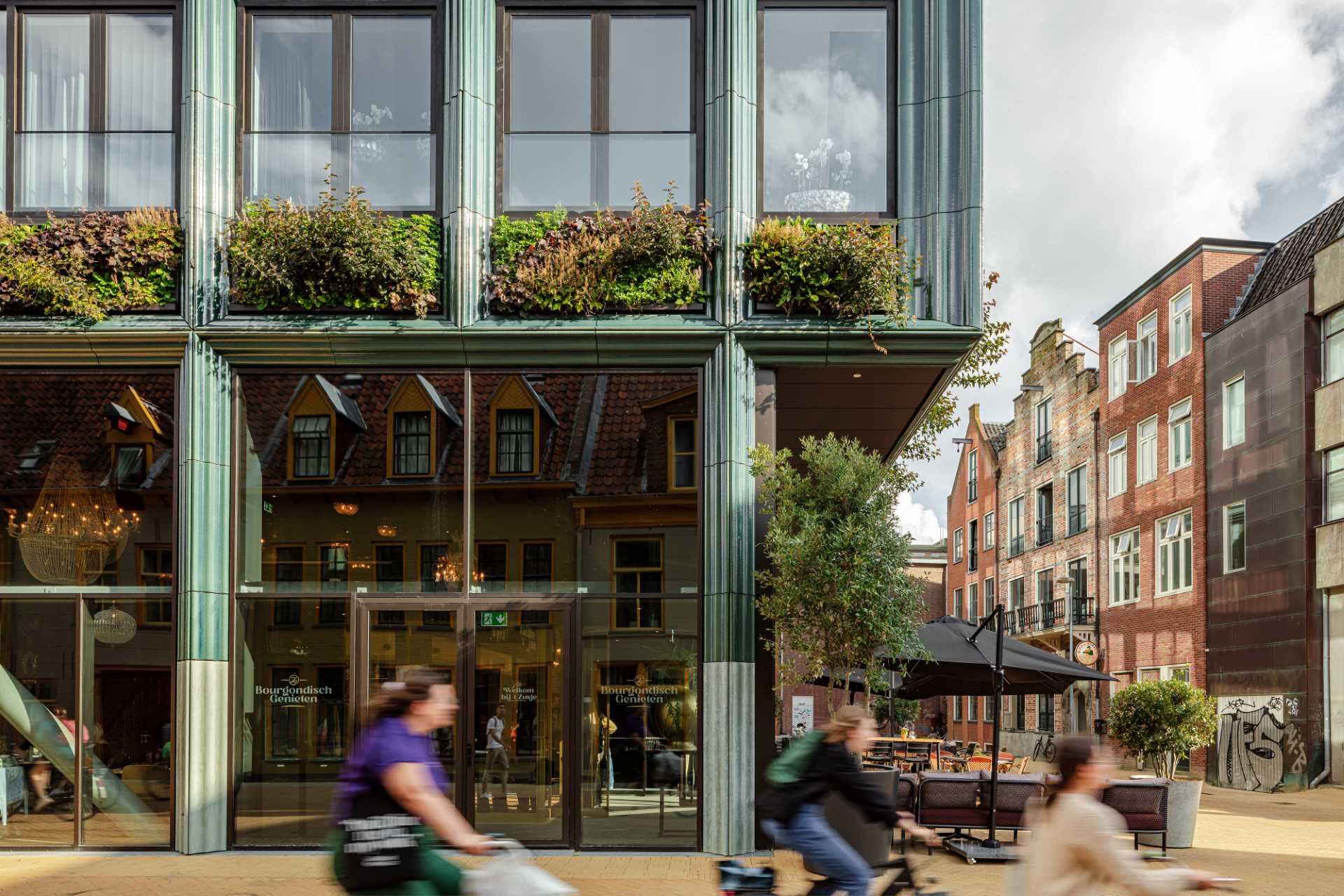 A modern building facade with glass, green walls, and blue-green ceramic details.