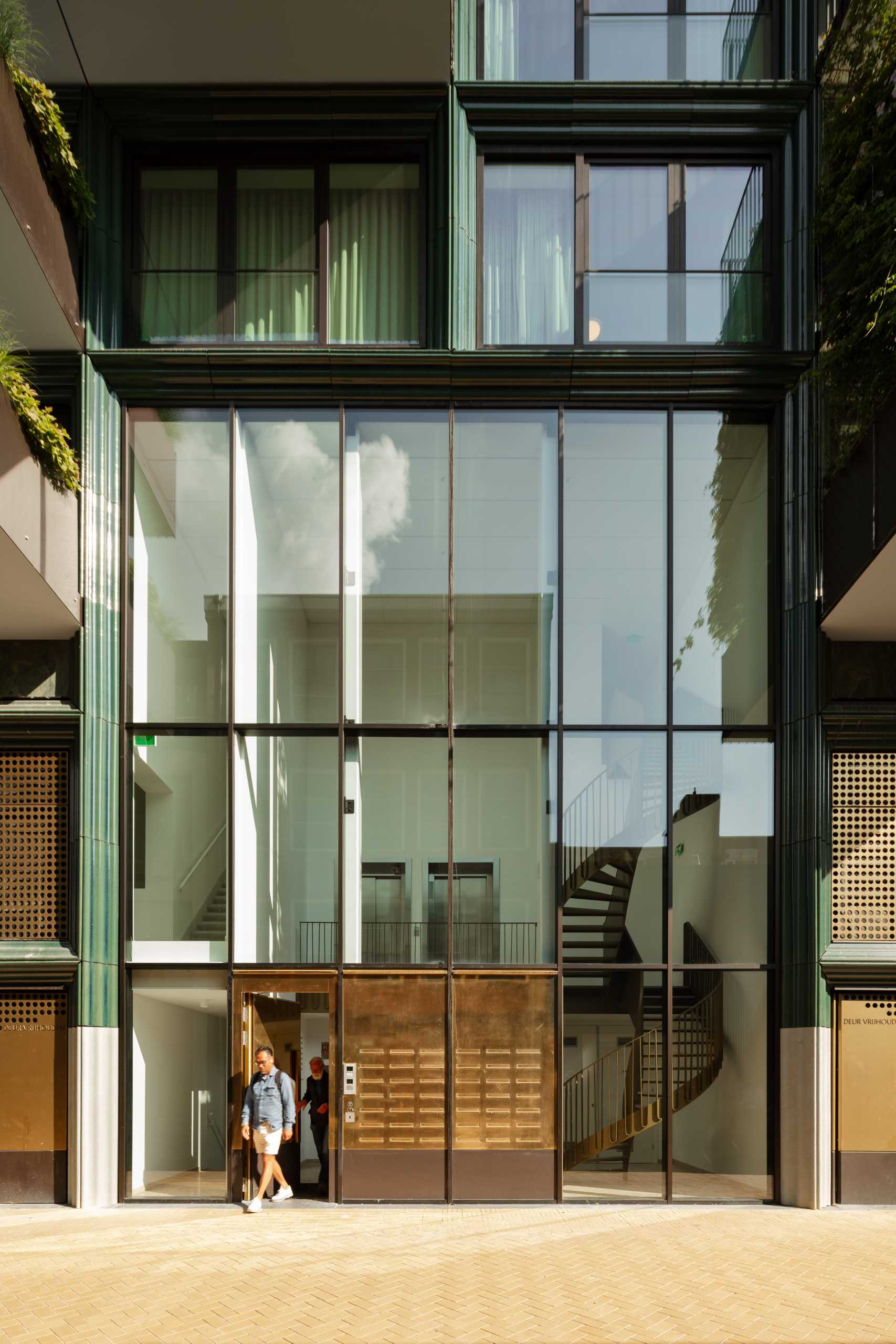 A modern building facade with glass and blue-green ceramic details.