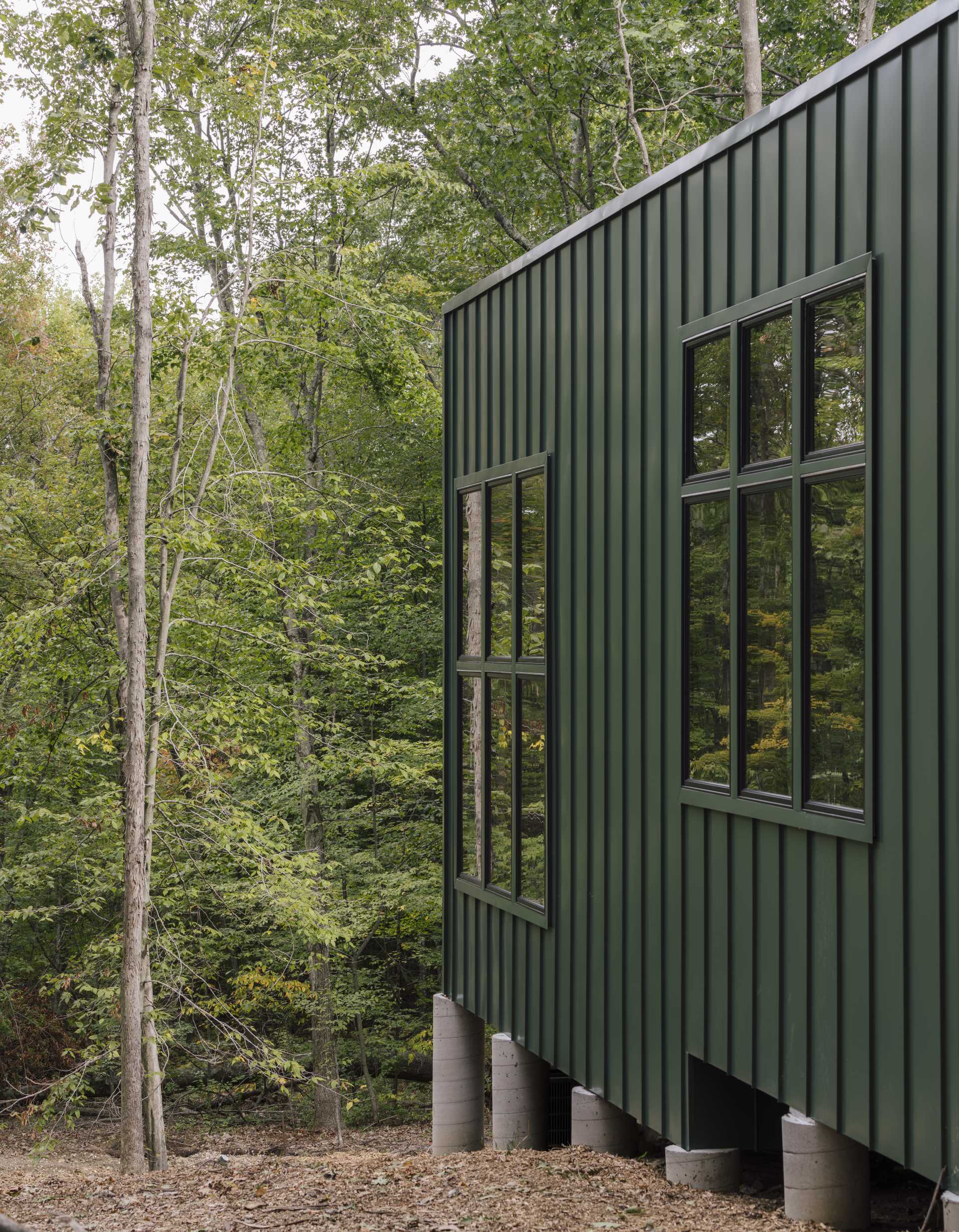 A modern two bedroom cabin with green metal standing seam siding and exposed wood structure.