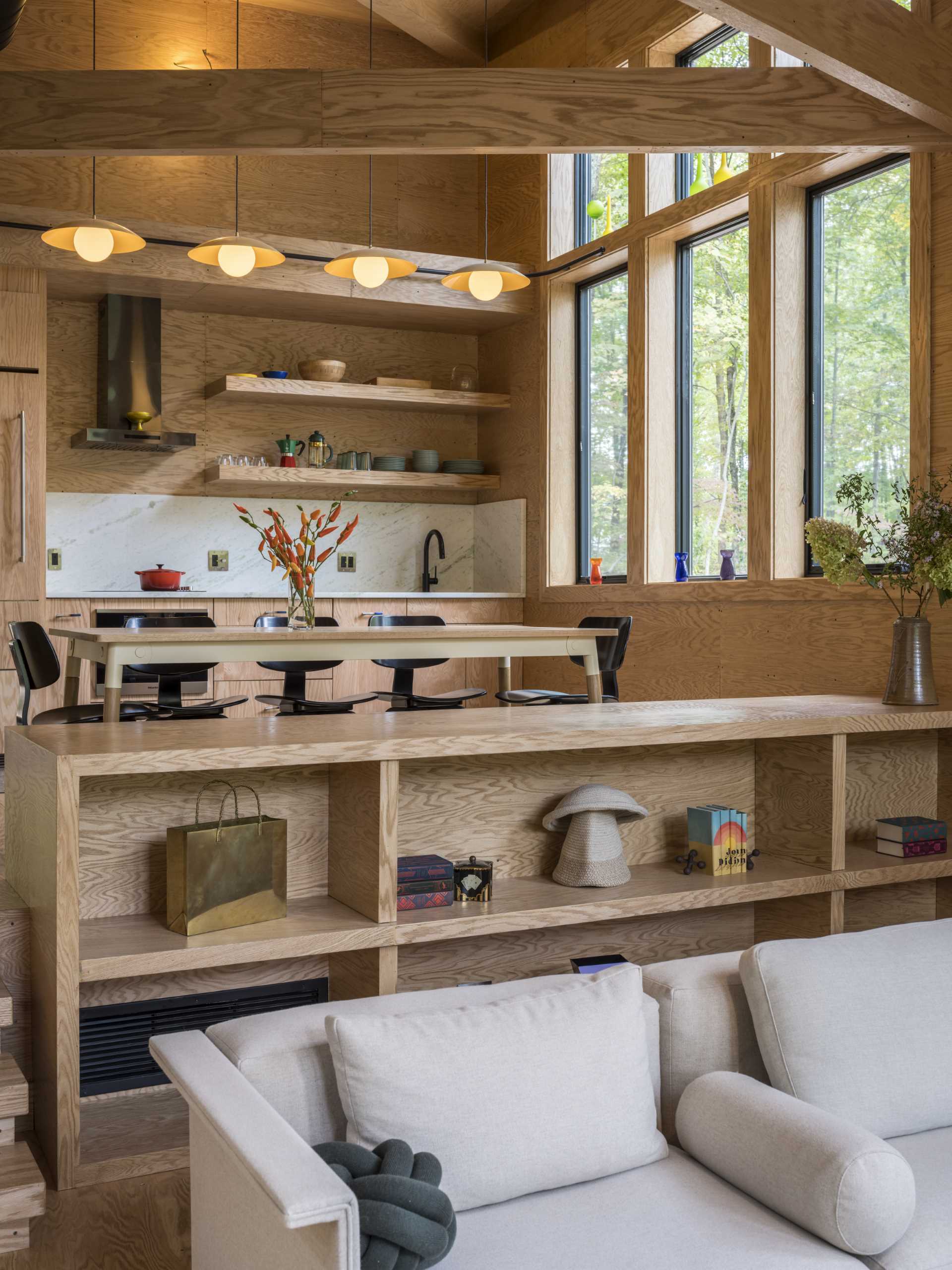 This dining area, which is located on a different level than the living room, is furnished with a wood table and black chairs, and separates the kitchen and living ،e.