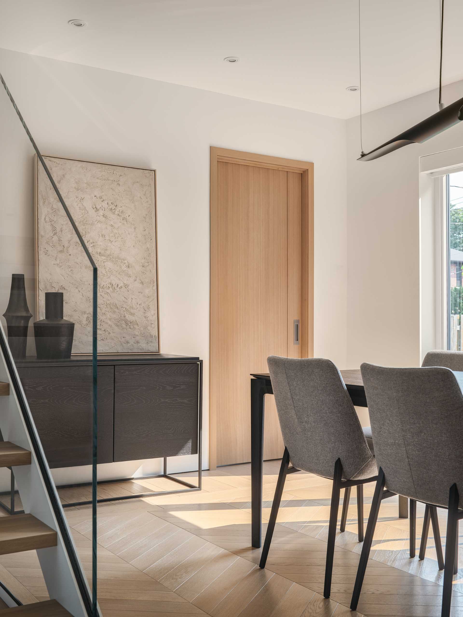 In this modern dining room, the wood flooring has been laid in a chevron pattern, while the dark dining table and sideboard create a contrasting element.