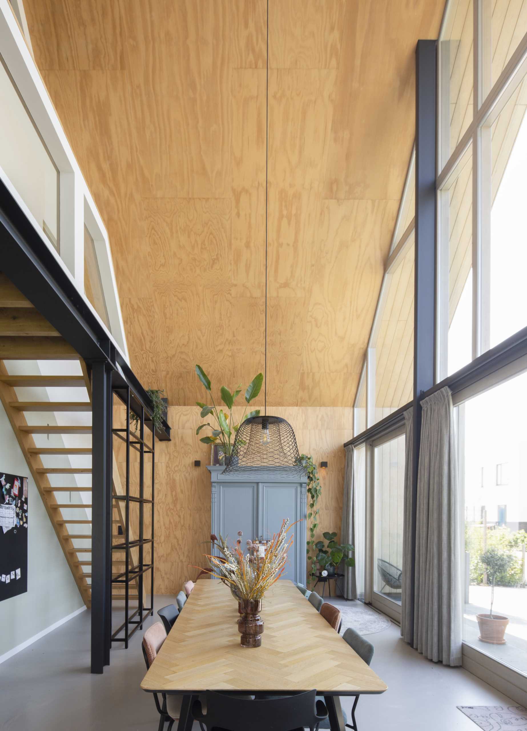 Plywood has been used as a design element in this dining area, and it that continues from the wall to the ceiling, and onto the first floor, creating a connection is created between the spaces.