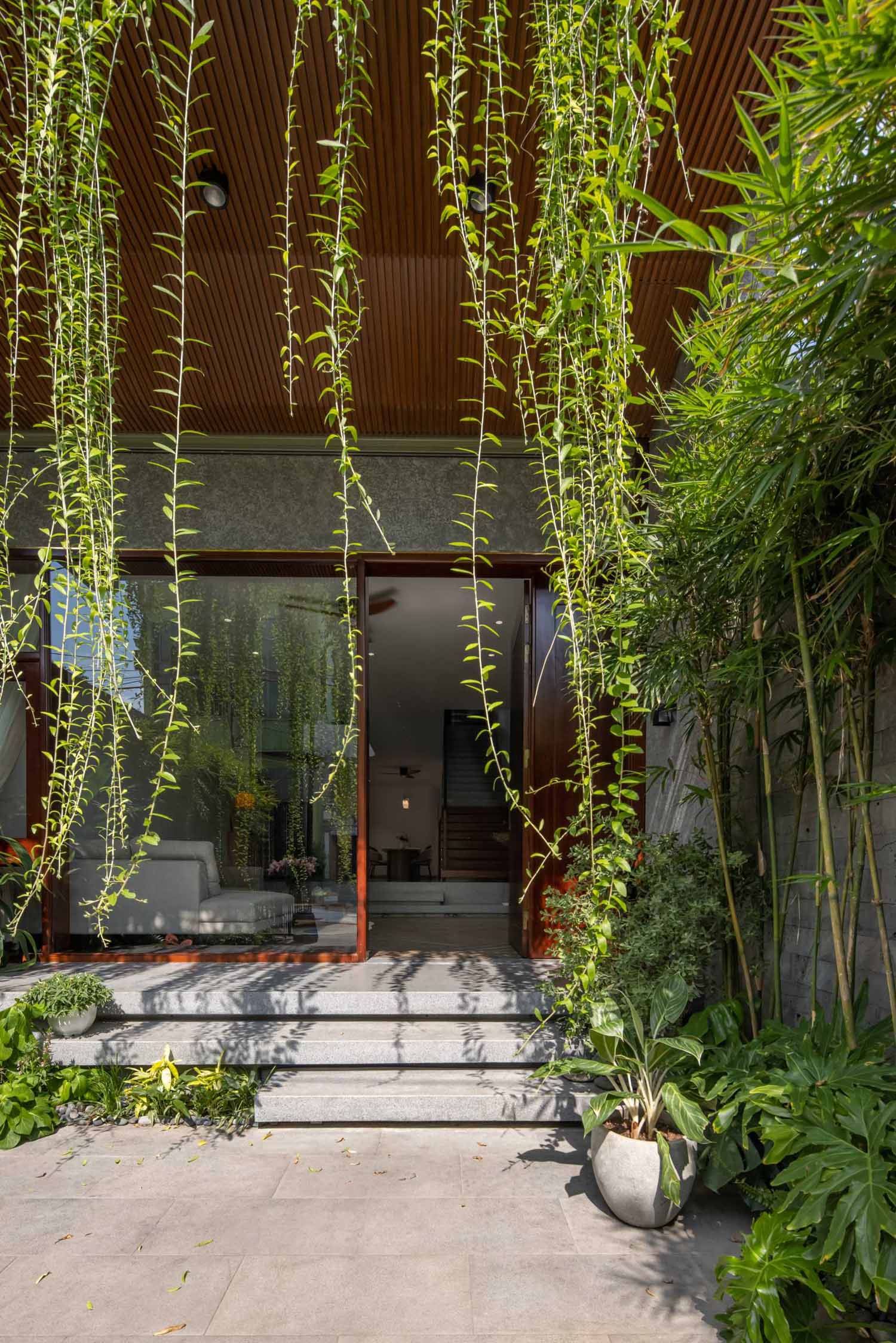 Steps lead from the front courtyard to the covered entryway, with the plants adding shade.