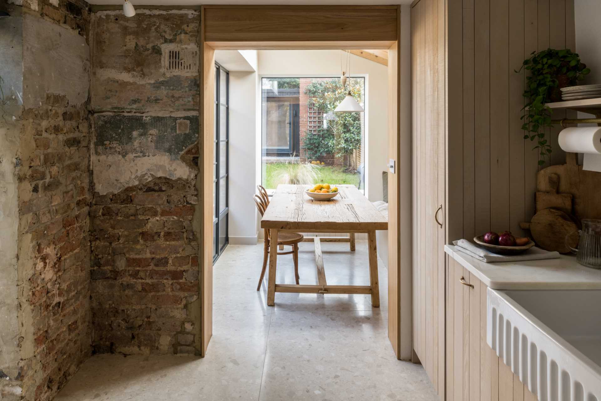 In this dining room, a built-in dining bench creates a cozy corner that provides a comfortable ledge and surrounds a rustic dining table made from reclaimed structural timbers.