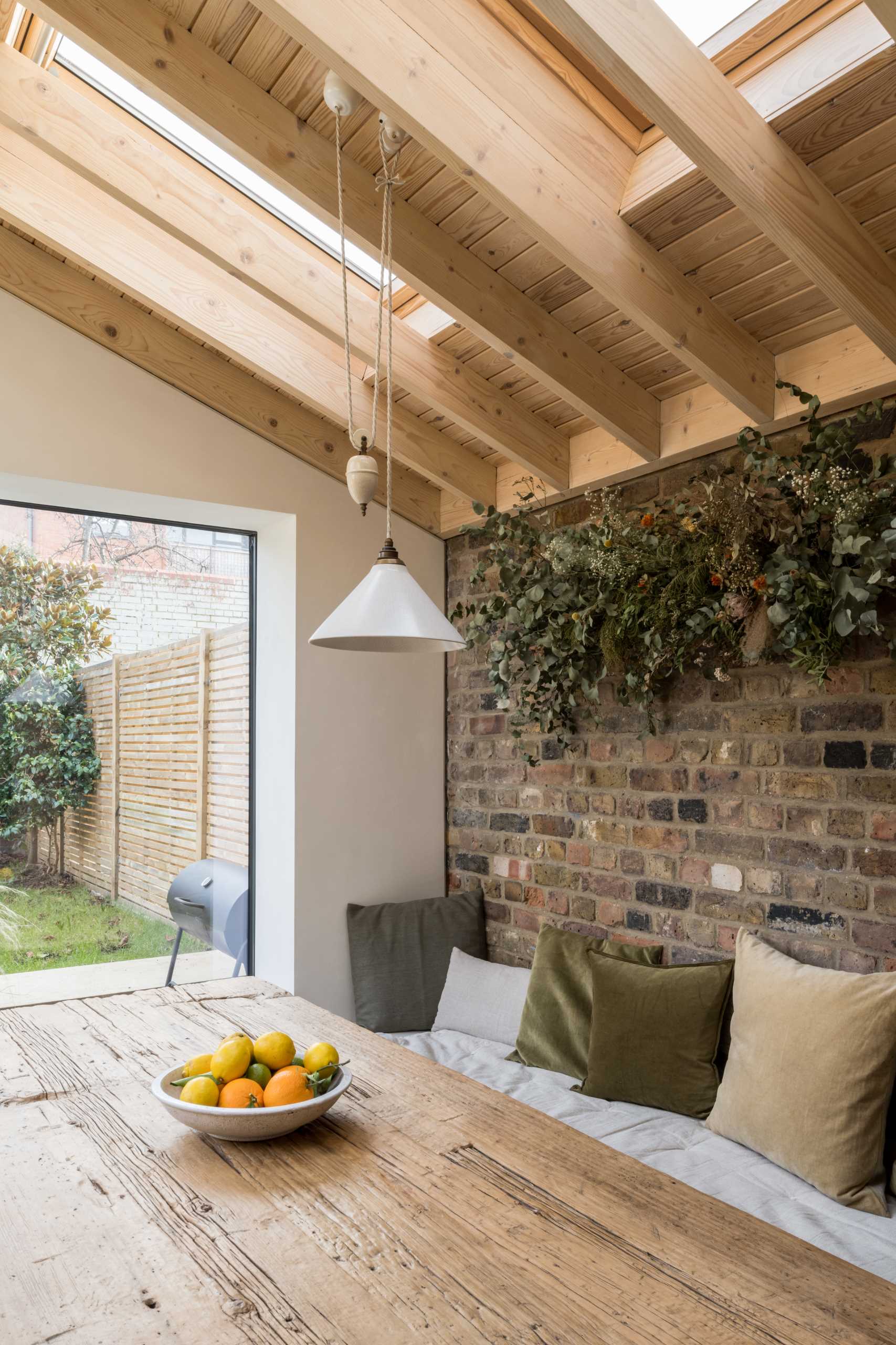 In this dining room, a built-in dining bench creates a cozy corner that provides a comfortable ledge and surrounds a rustic dining table made from reclaimed structural timbers.