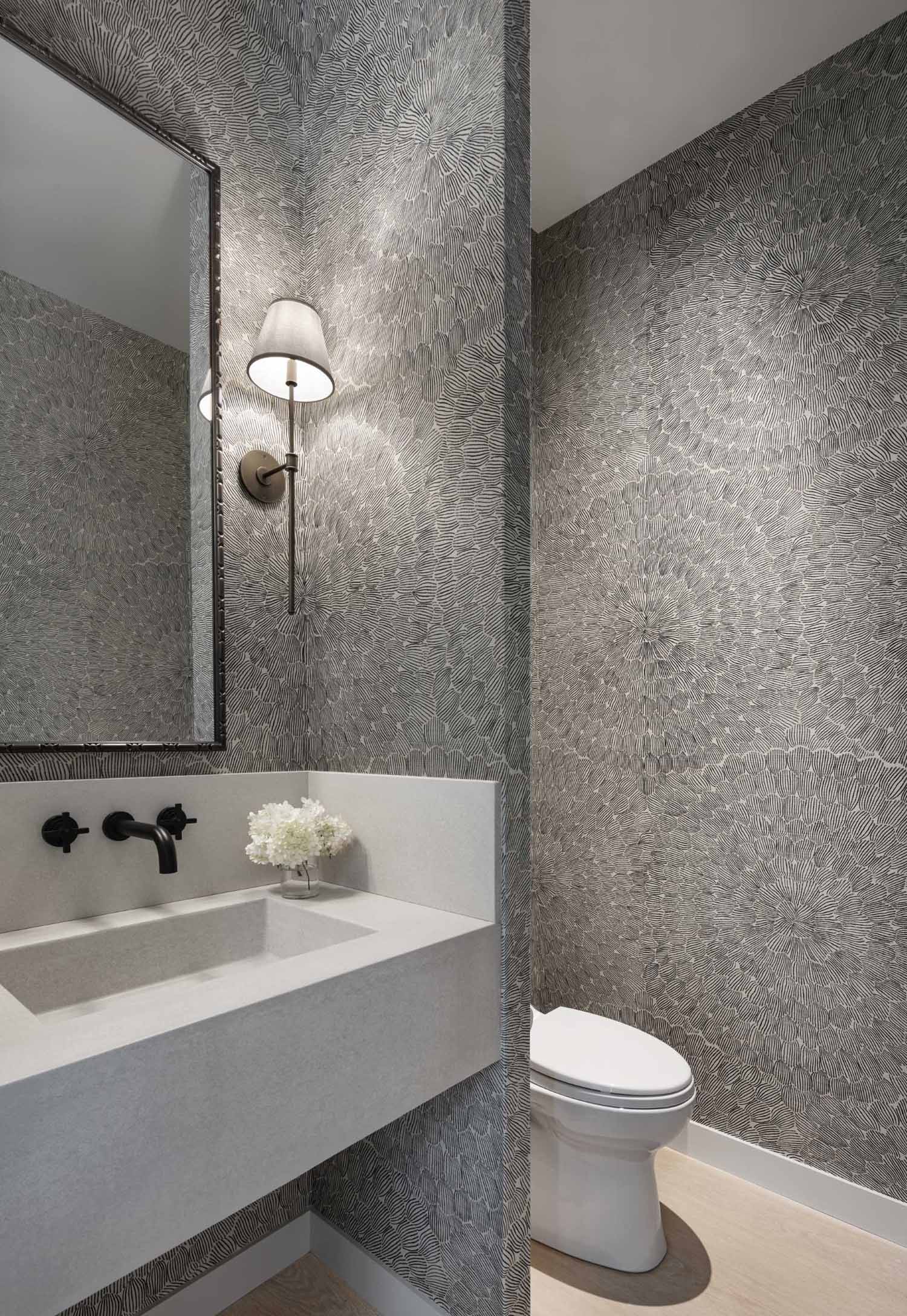 A black and white patterned wallpaper covers the walls of this powder room.
