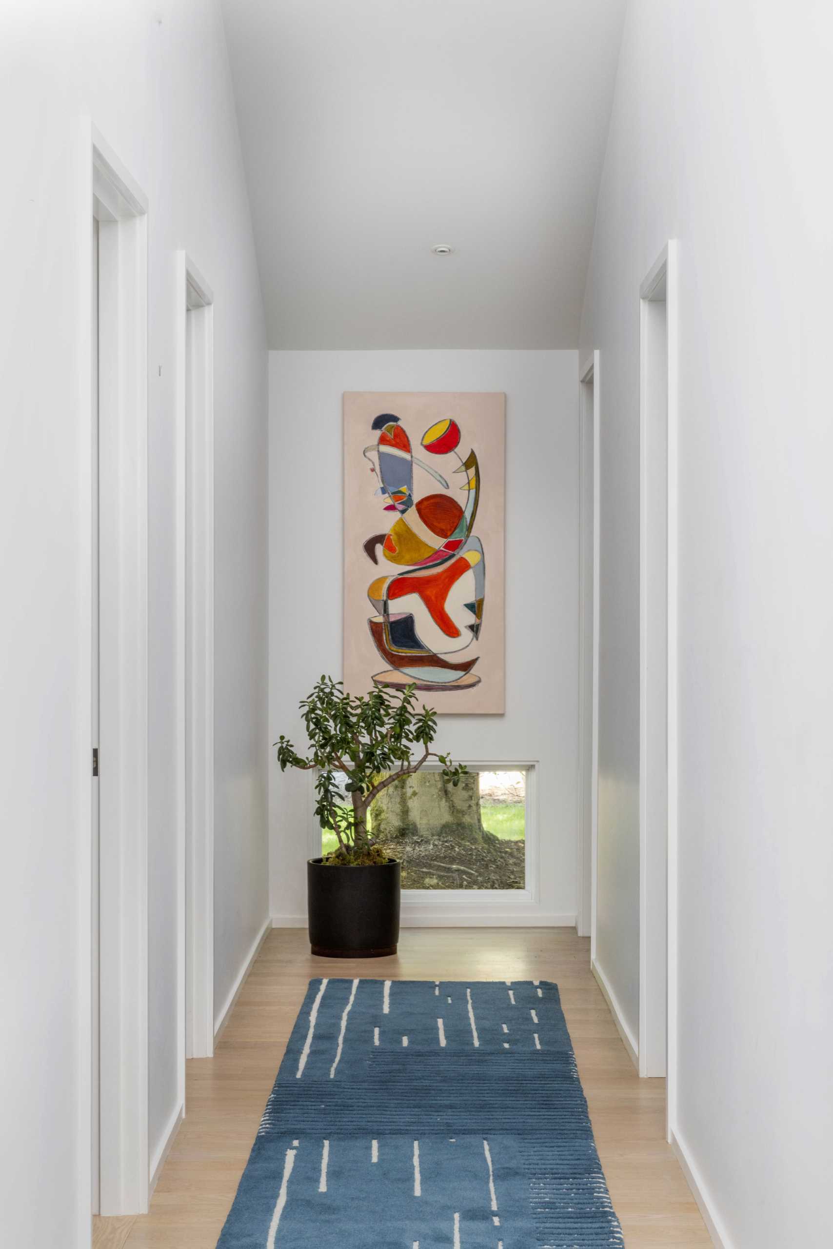 An updated hallway has a low window to let natural light in.