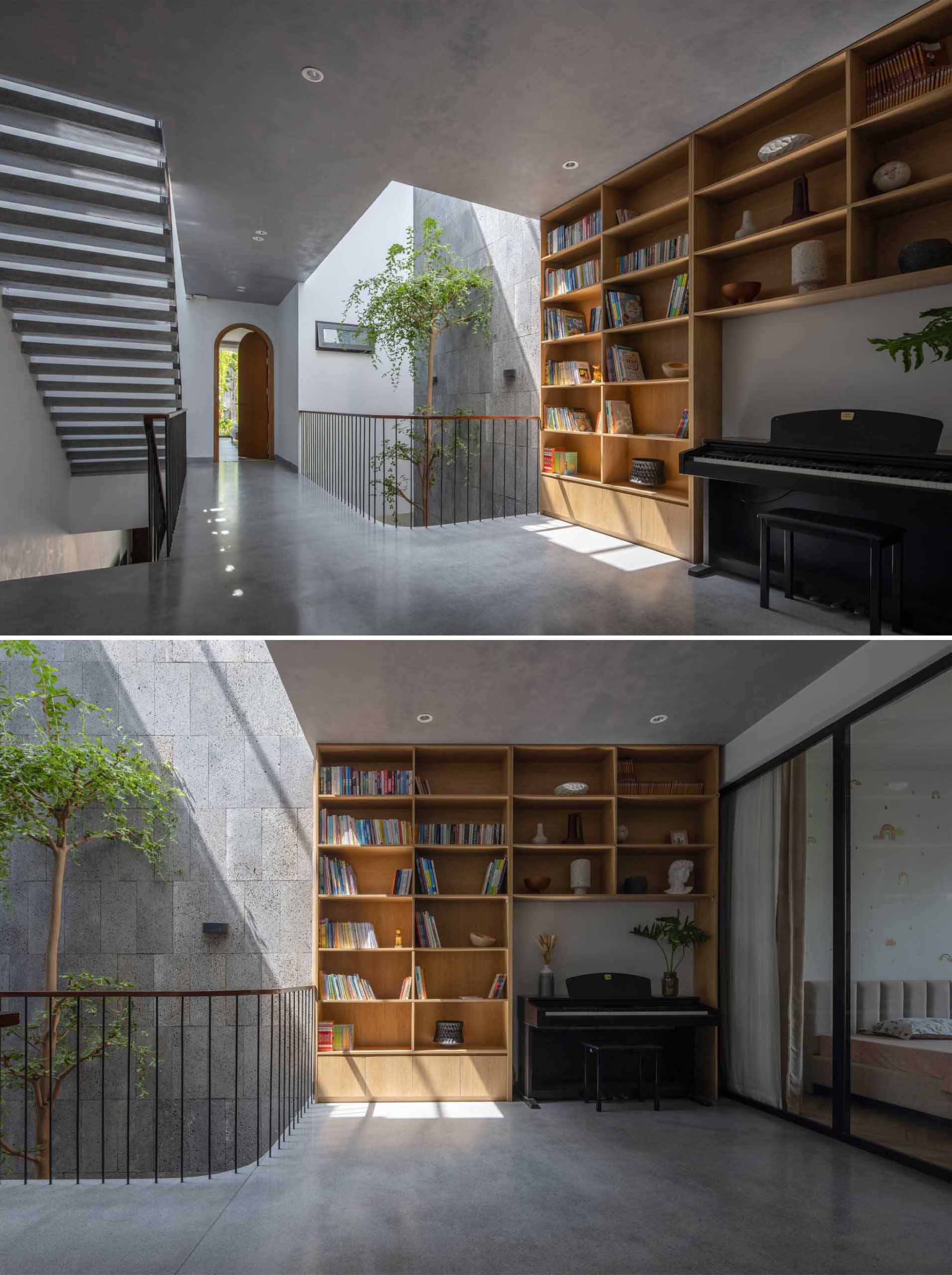 On the second floor of this modern home, there's a public space with a wood bookshelf, a piano, and a couch.