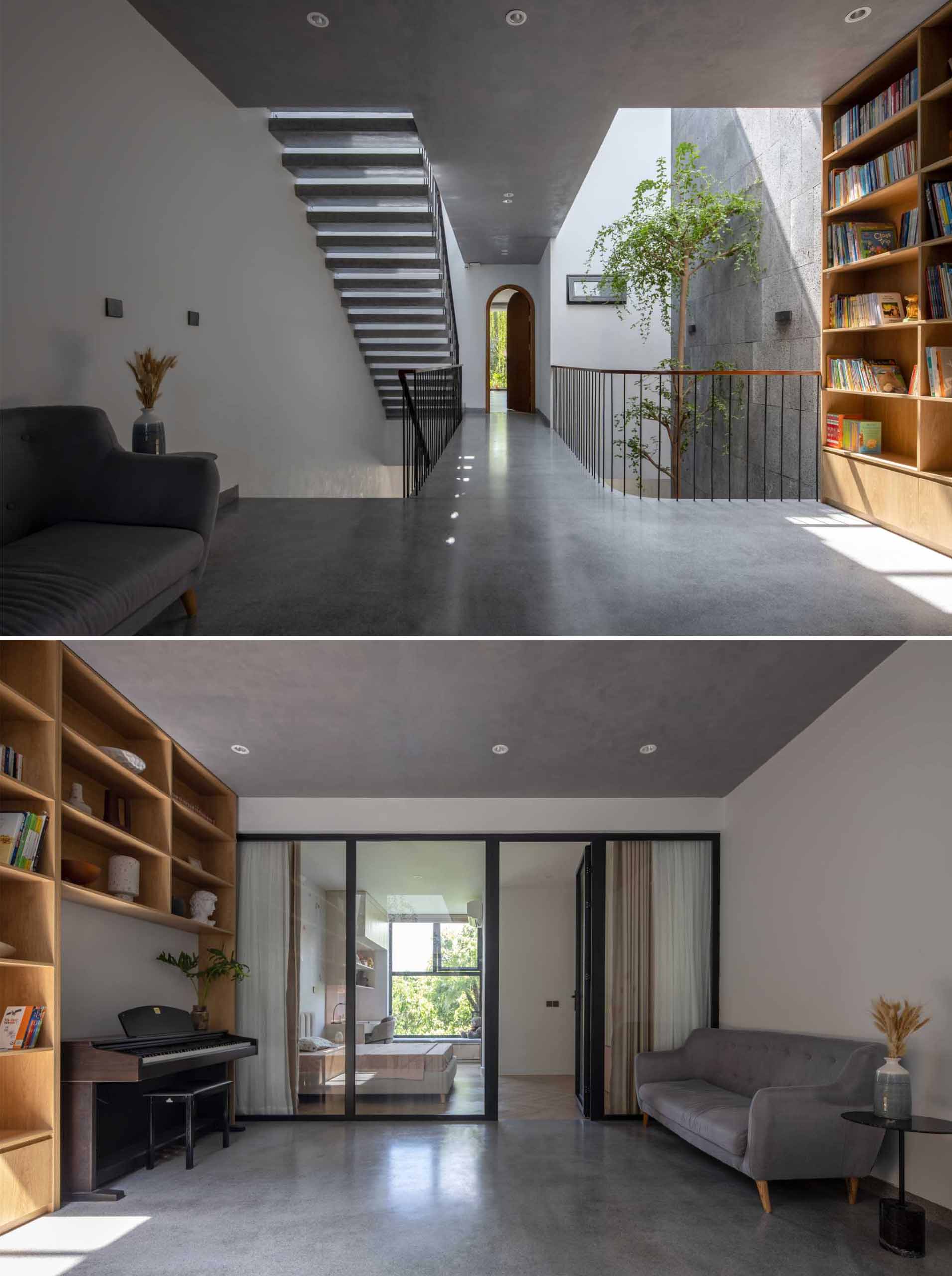 On the second floor of this modern home, there's a public space with a wood bookshelf, a piano, and a couch.