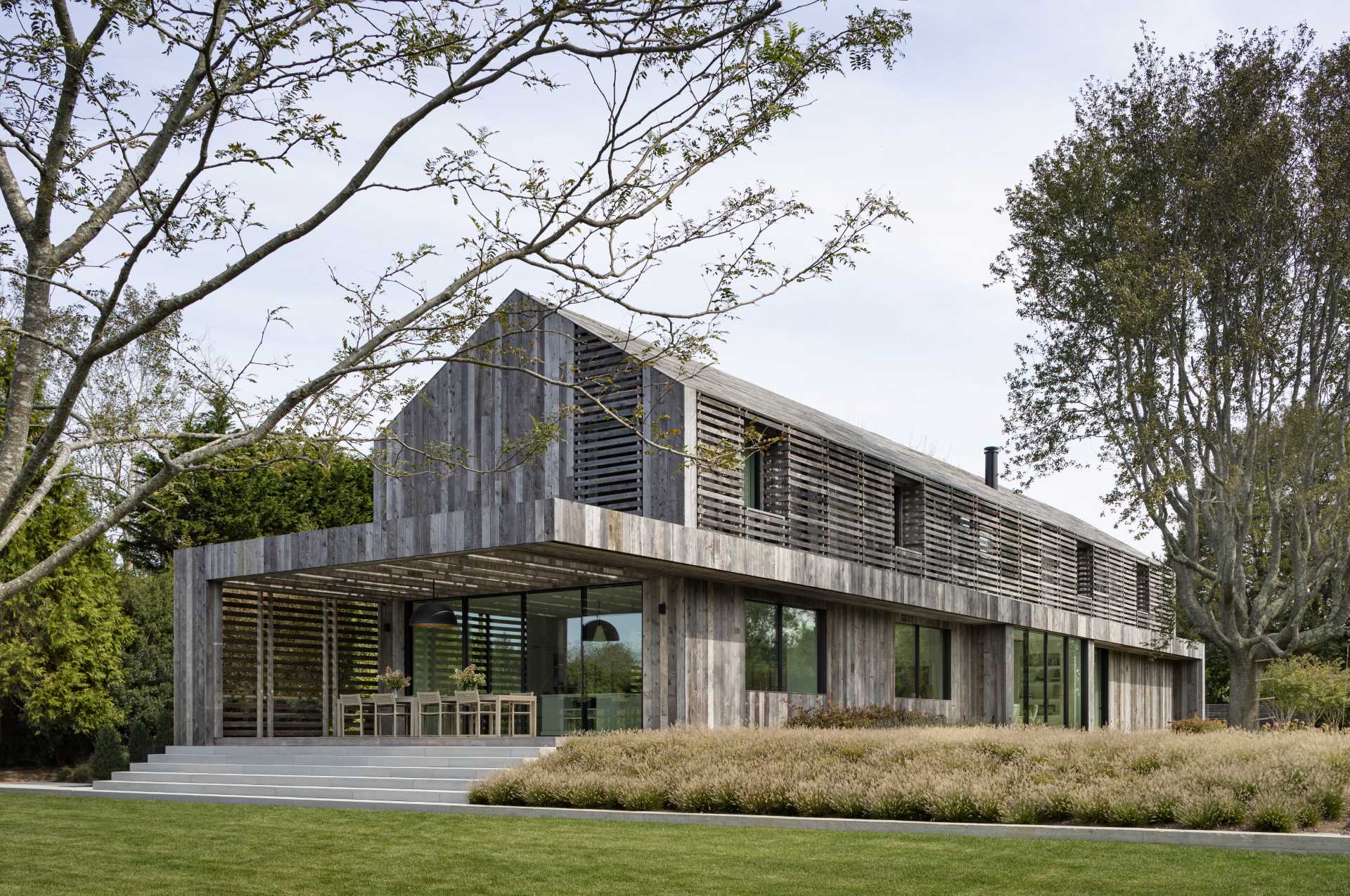 A modern two-story gabled home is clad in reclaimed weathered wood siding.