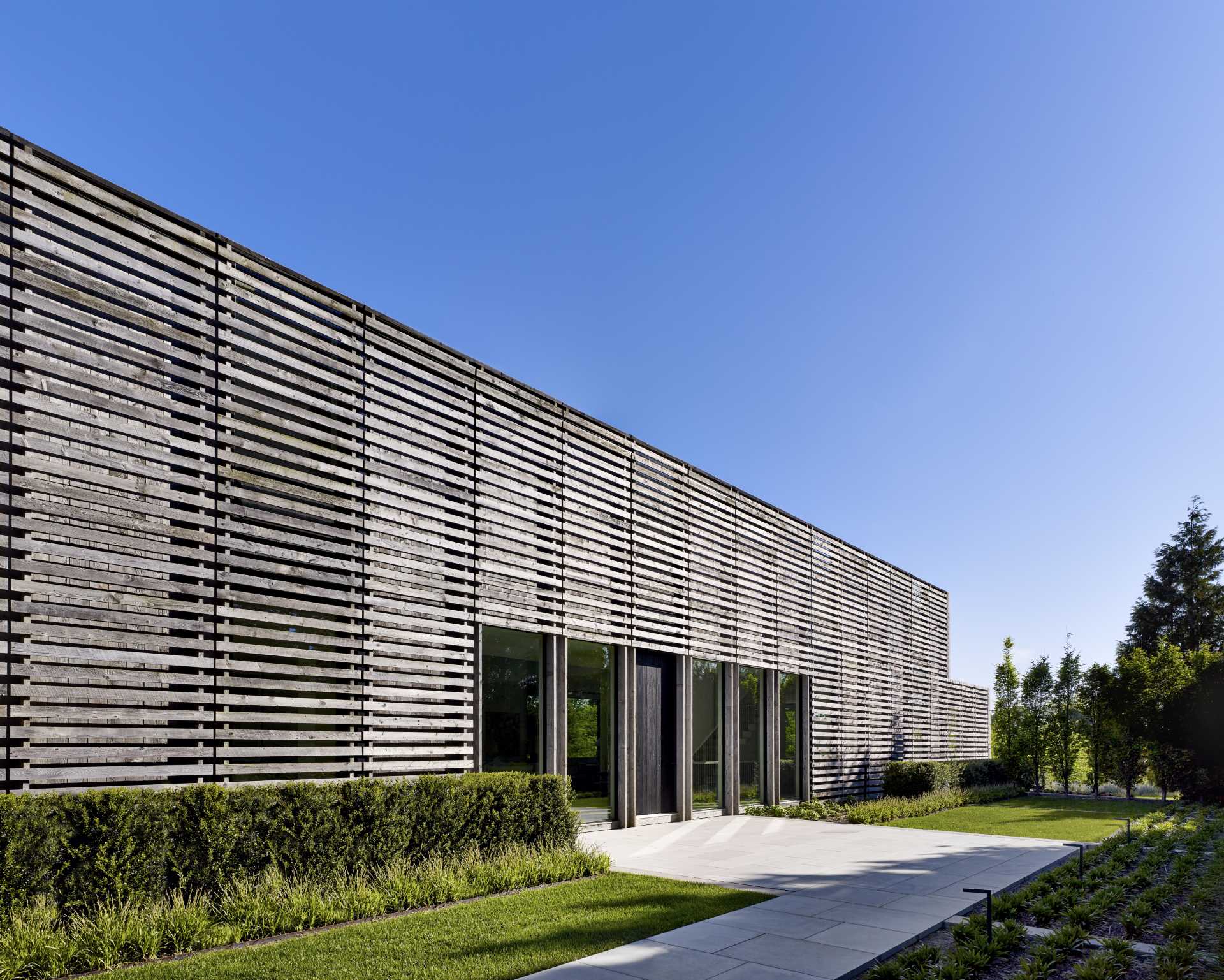 A modern two-story gabled home is clad in reclaimed weathered wood siding.