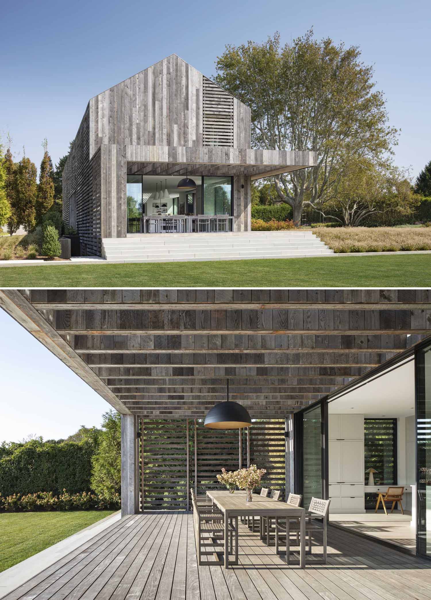 A modern home clad in reclaimed wood has a porch for outdoor dining.