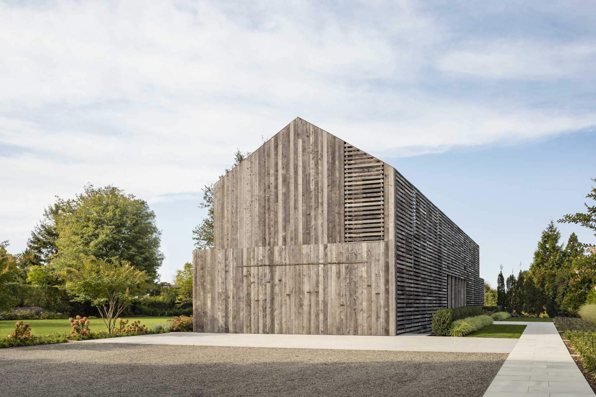 A modern two-story gabled home is clad in reclaimed weathered wood siding.