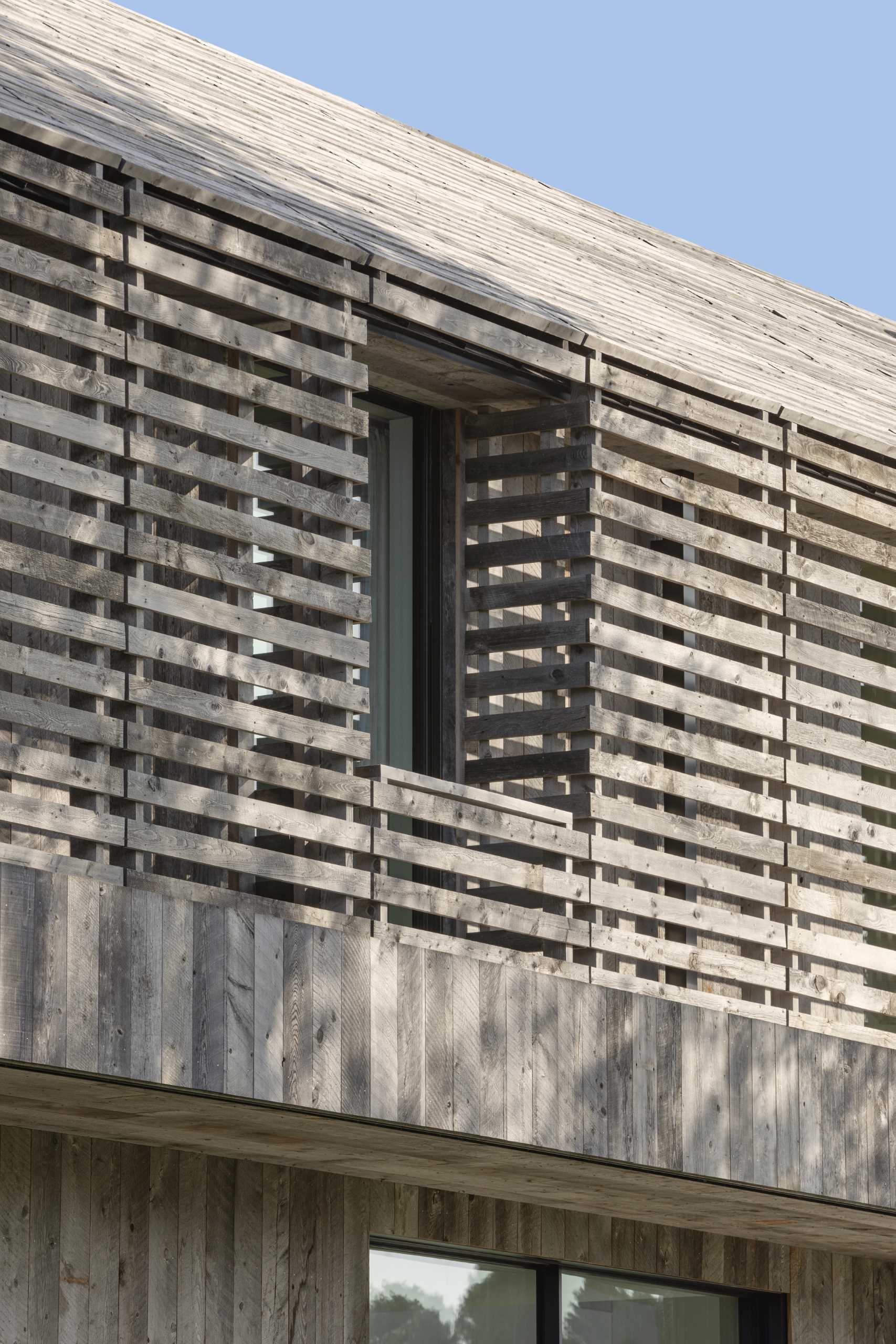 A modern two-story gabled home is clad in reclaimed weathered wood siding.