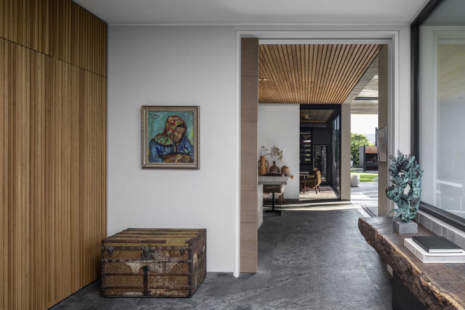 Stepping inside this modern home, the entryway features a wood accent wall that complements the wood ceiling that can be seen in the kitchen.