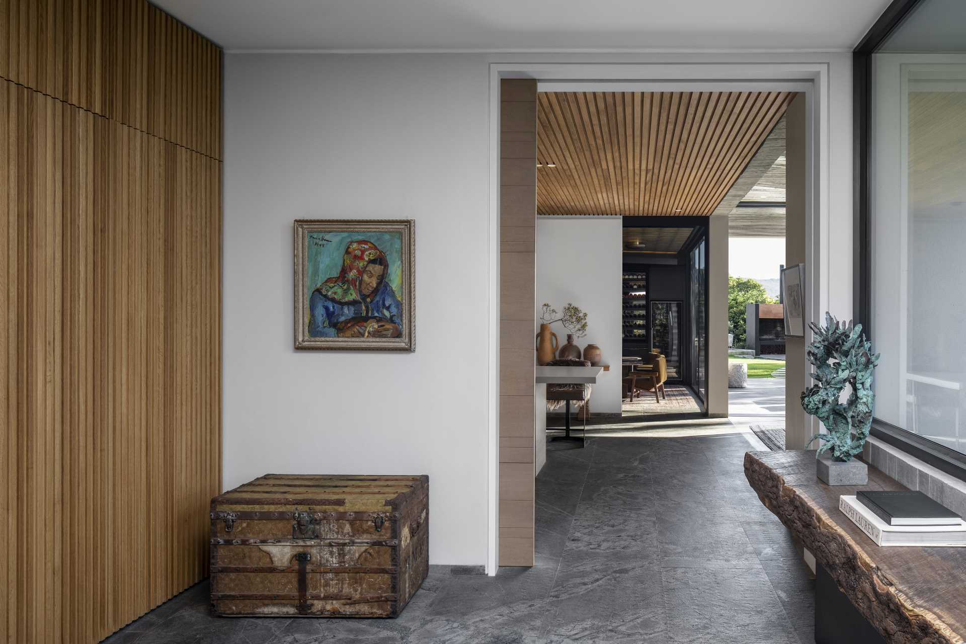 Stepping inside this modern ،me, the entryway features a wood accent wall that complements the wood ceiling that can be seen in the kitchen.