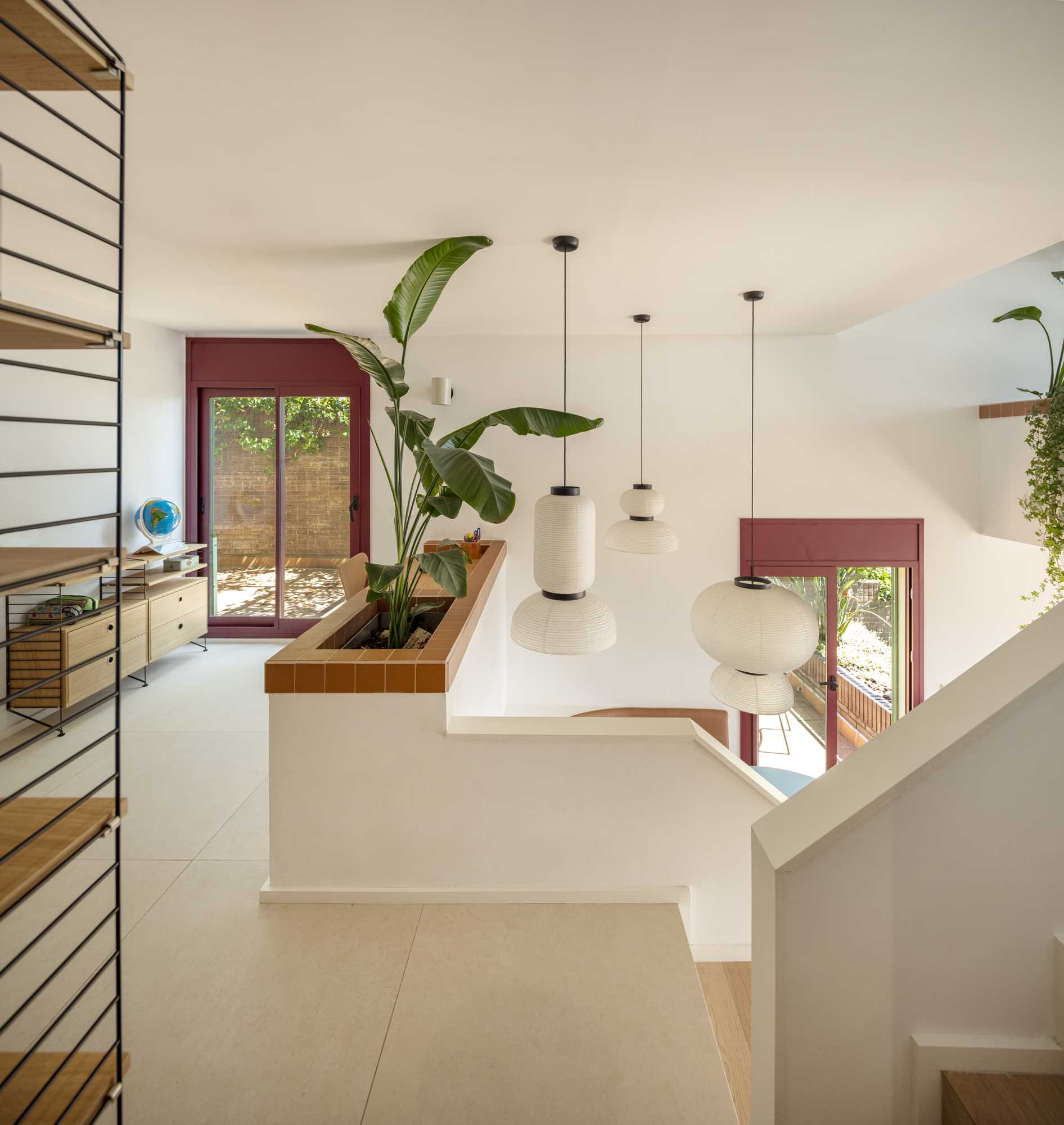 Stepping inside this modern interior, there's a small entryway with a built-in planter and a desk that overlooks the living room below.