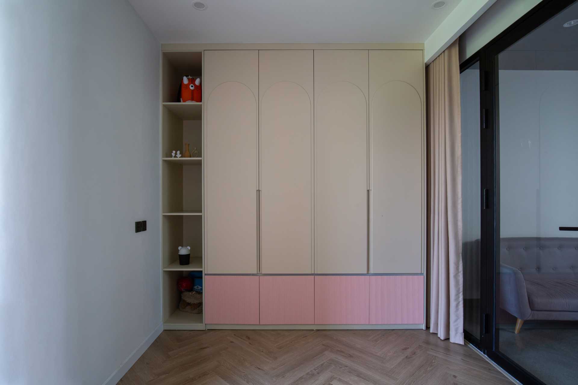 In this kids' bedroom, there's a custom-designed desk with shelving and cabinetry, as well as a bench underneath the window. On the opposite wall, there's the door to the ensuite bathroom and a floor-to-ceiling closet.