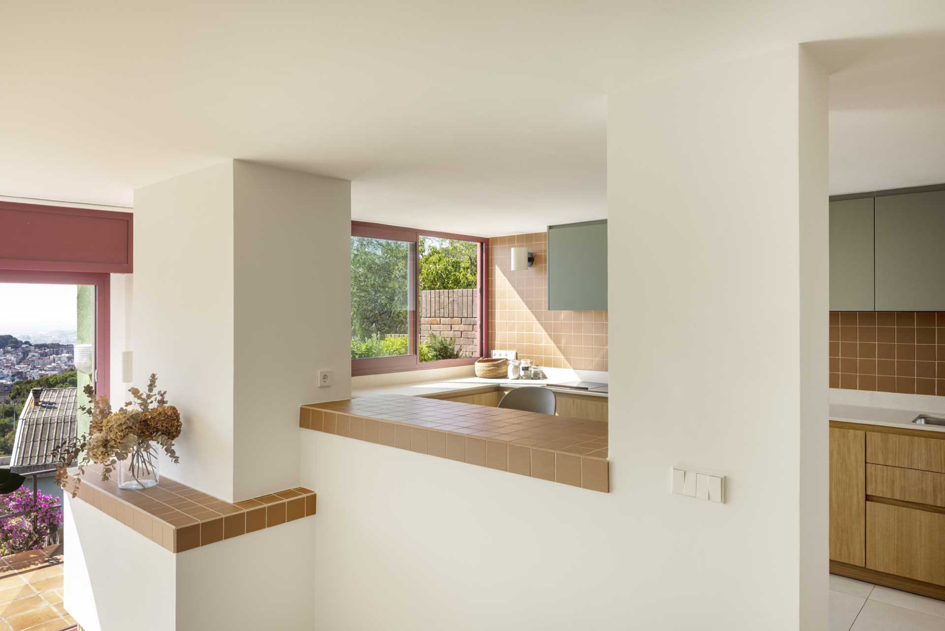 A contemporary kitchen with wood and sage green cabinets and terracotta colored tiles.