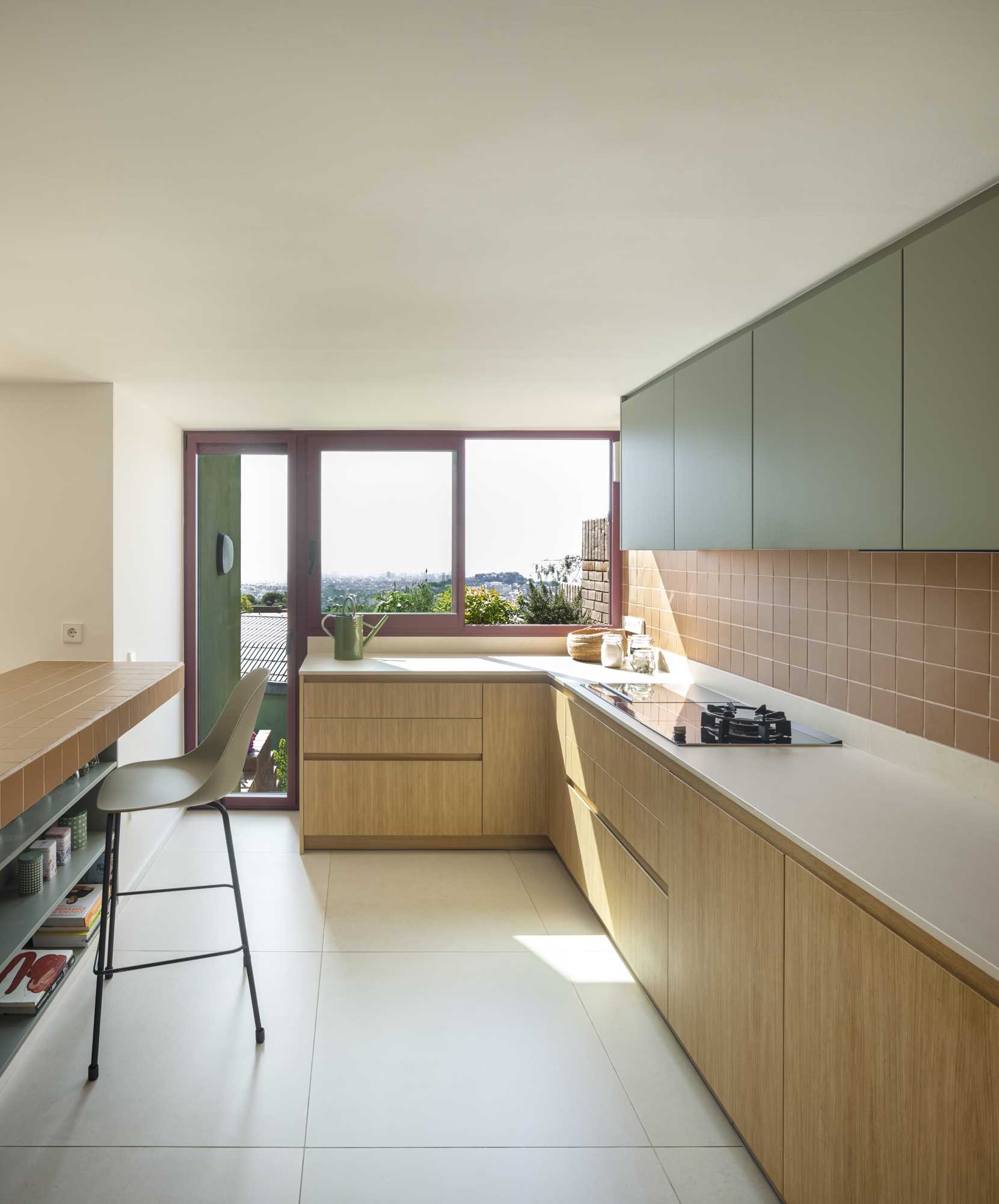 A contemporary kitchen with wood and sage green cabinets and terracotta colored tiles.