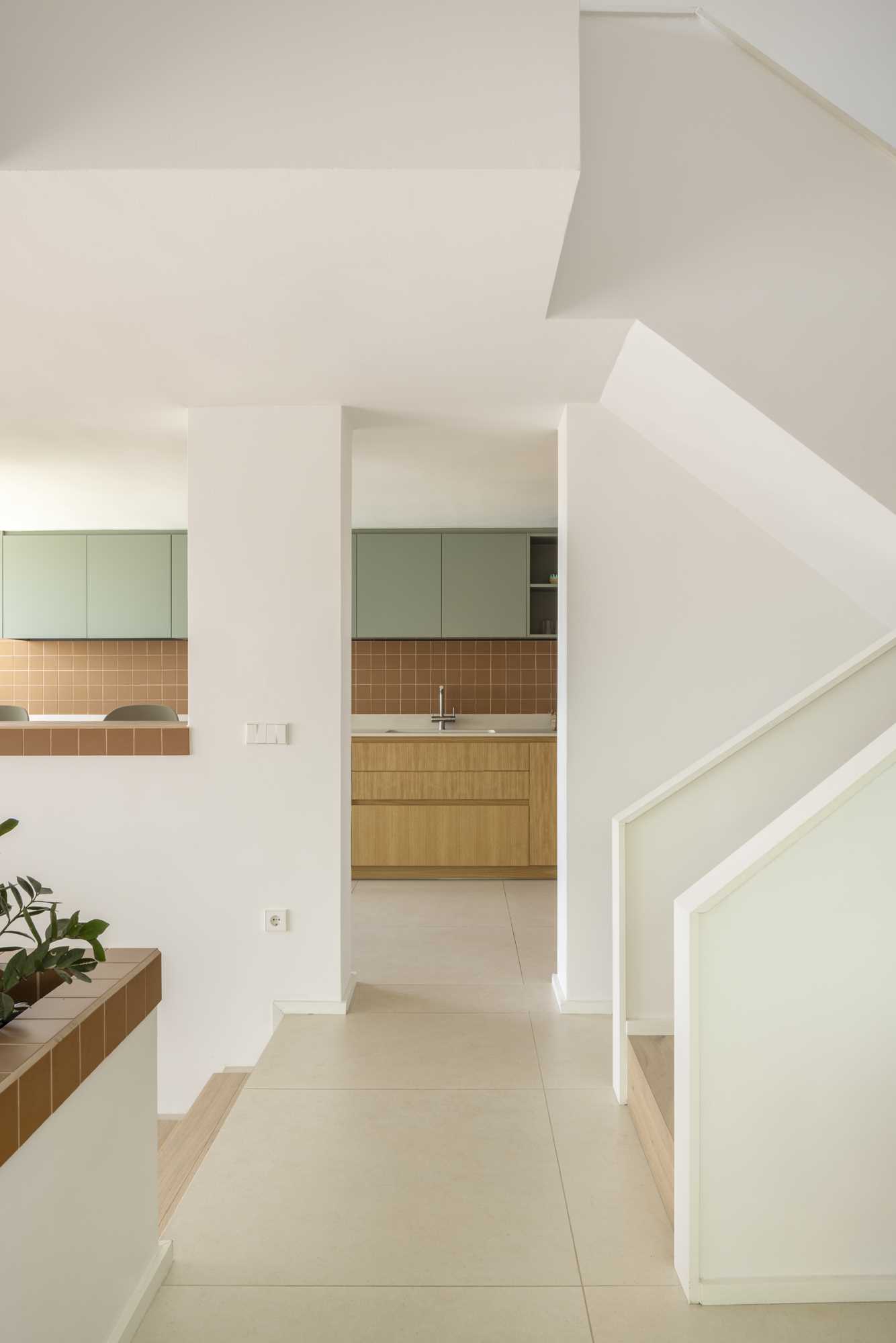 A contemporary kitchen with wood and sage green cabinets and terracotta colored tiles.