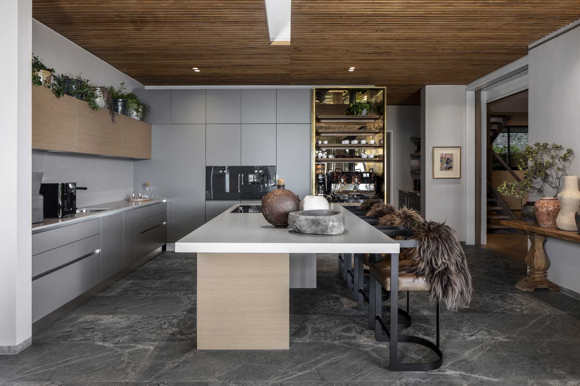 In this modern kitchen, minimalist matte grey cabinets line the walls, while the island adds counter space.