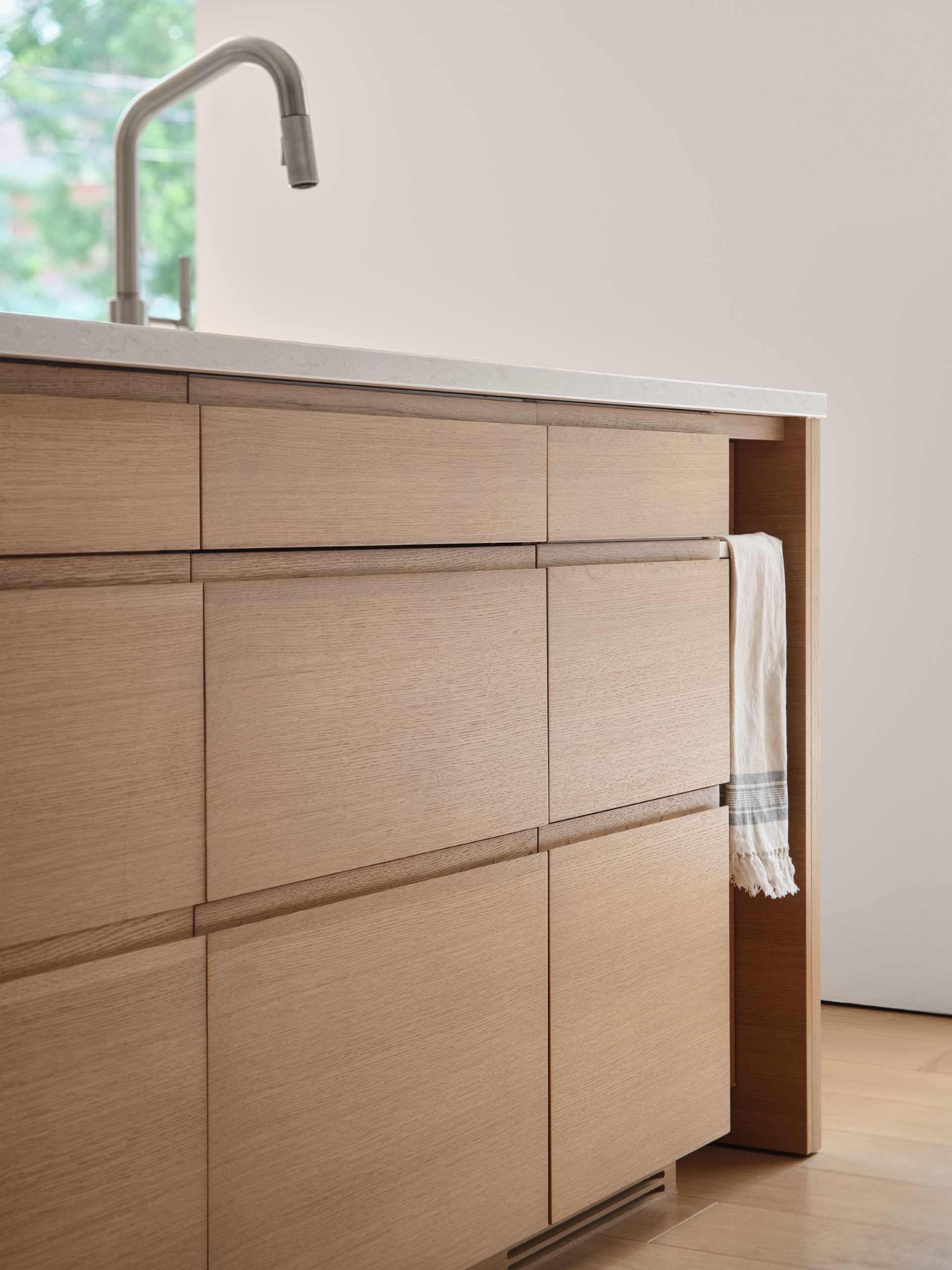 In this modern kitchen, an island creates additional storage and room for seating, while an open shelf built into the wall provides a place to display dinnerware and glassware.