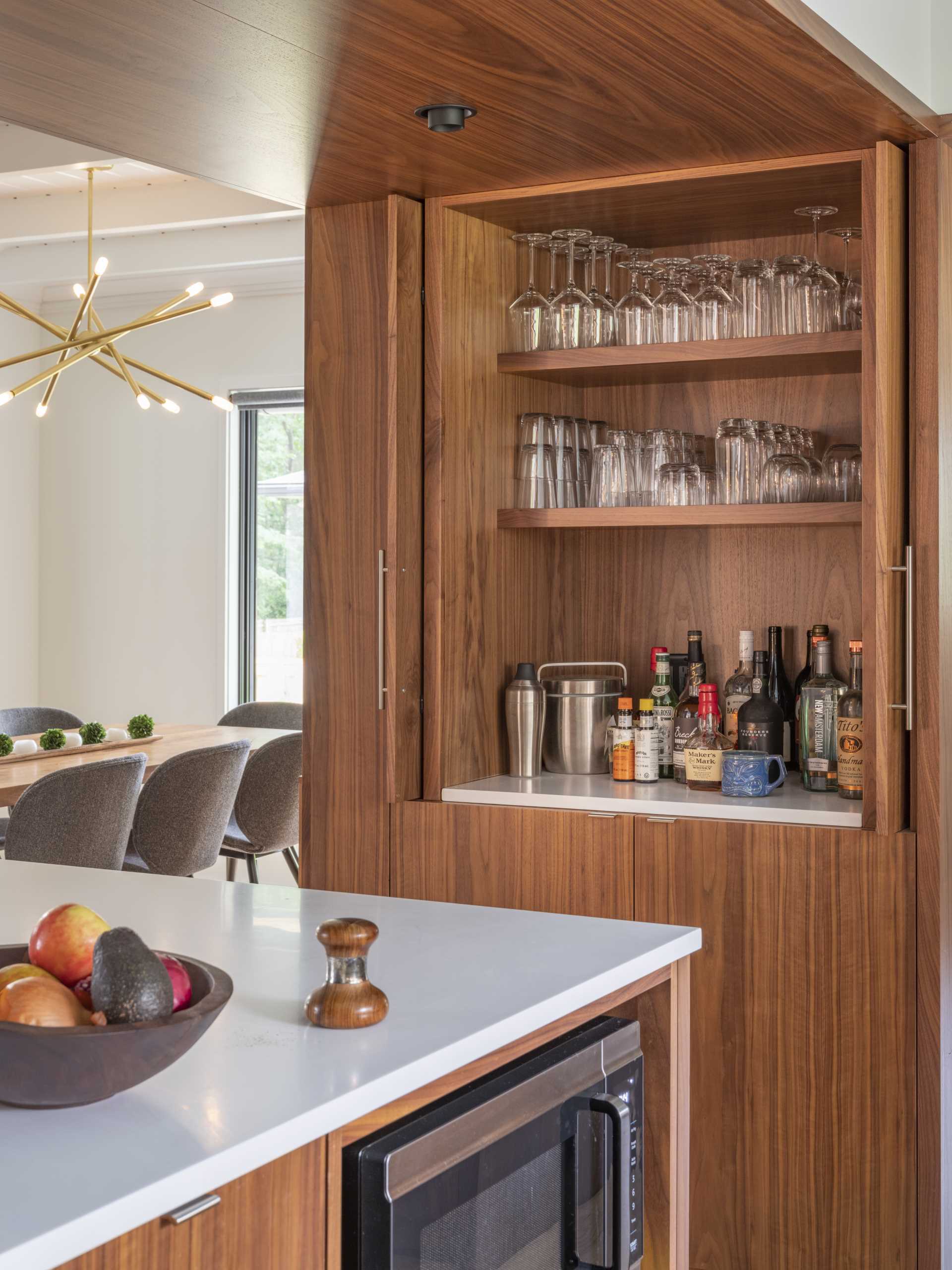 In this updated kitchen, wood cabinetry has been paired with white countertops with matching white tiles, and a light blue ceiling.