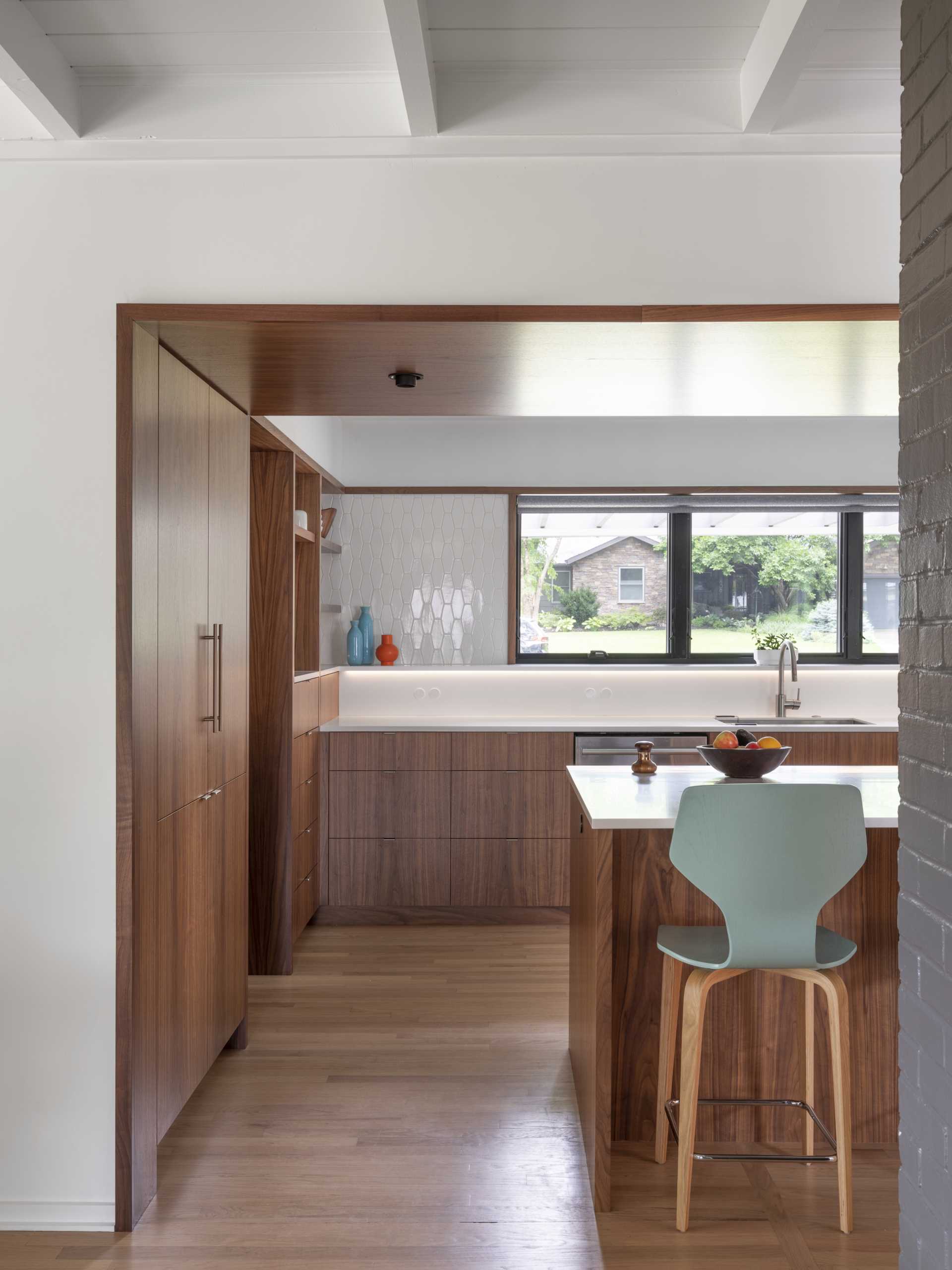 In this updated kitchen, wood cabinetry has been paired with white countertops with matching white tiles, and a light blue ceiling.