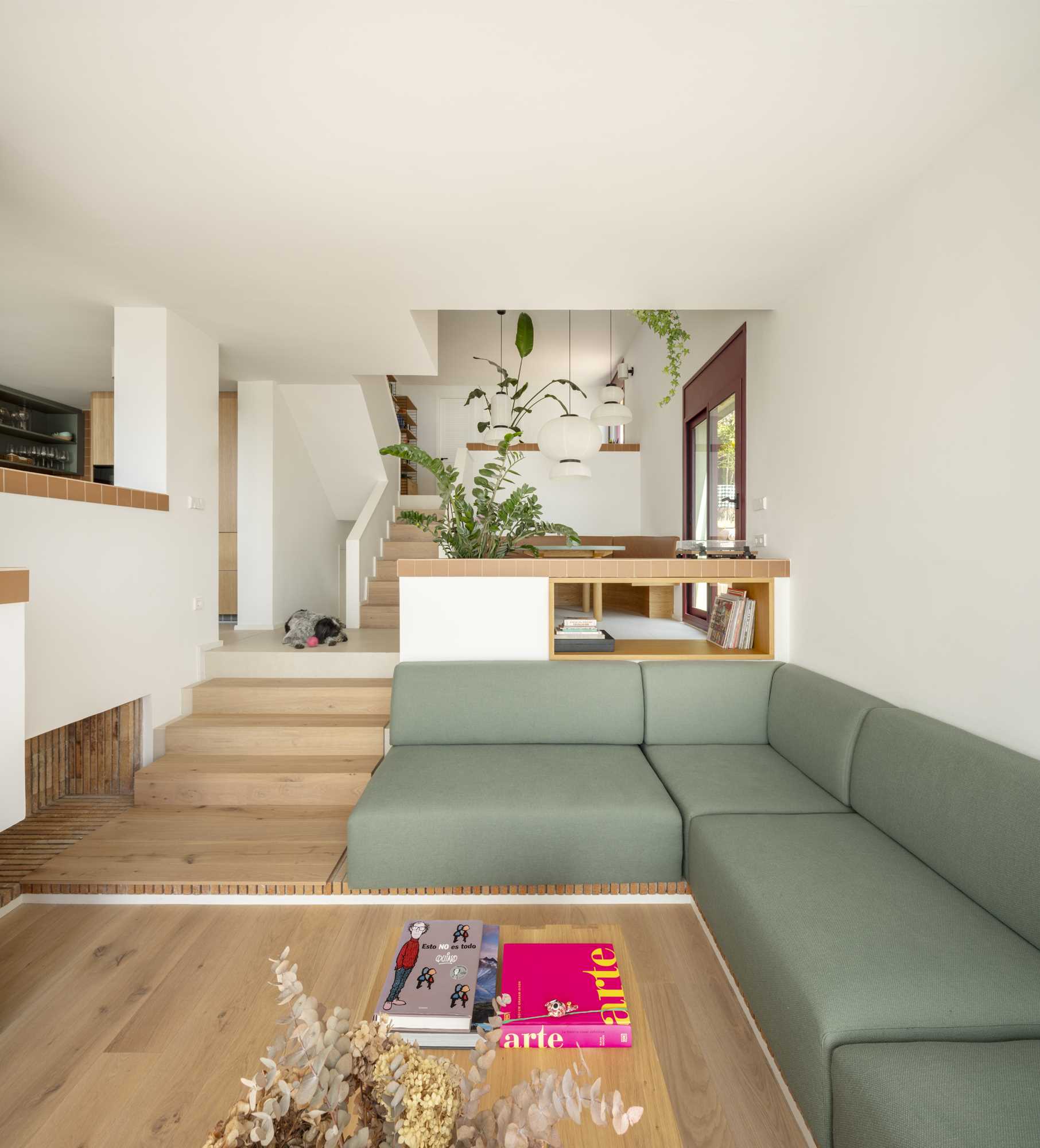 A contemporary home interior with split-levels that include built-in planters and a green couch in the living room.