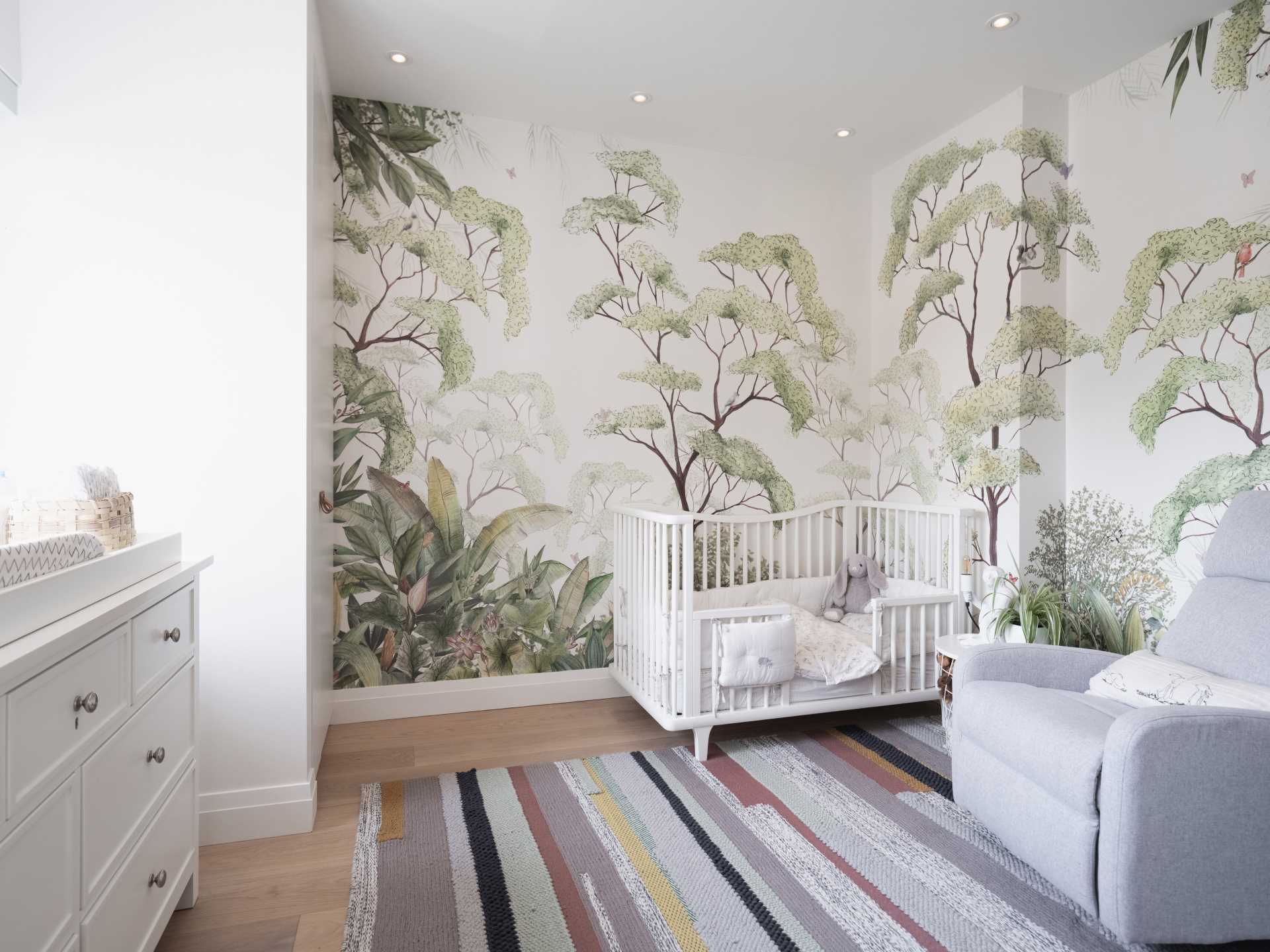 In this modern kids bedroom, a forest mural has been applied to the wall, adding a natural element to the space.