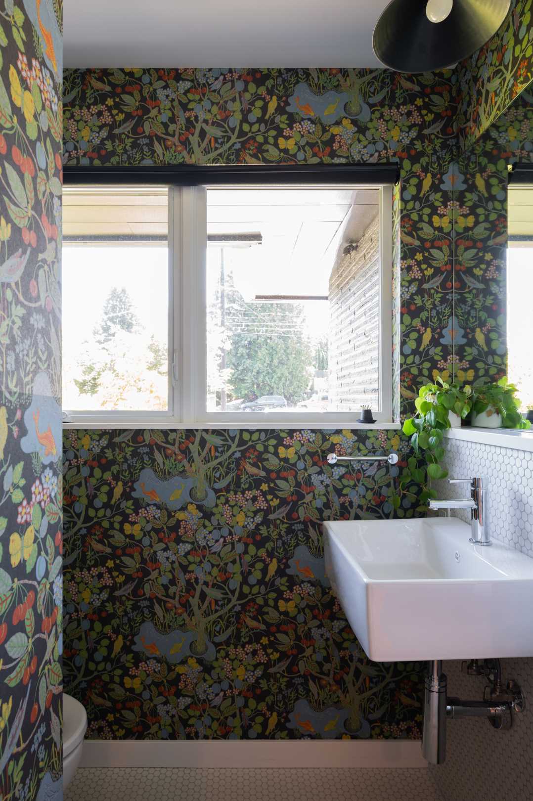 A botanical wallpaper adorns the walls in this powder room, creating an unexpected pop of color in the small space.