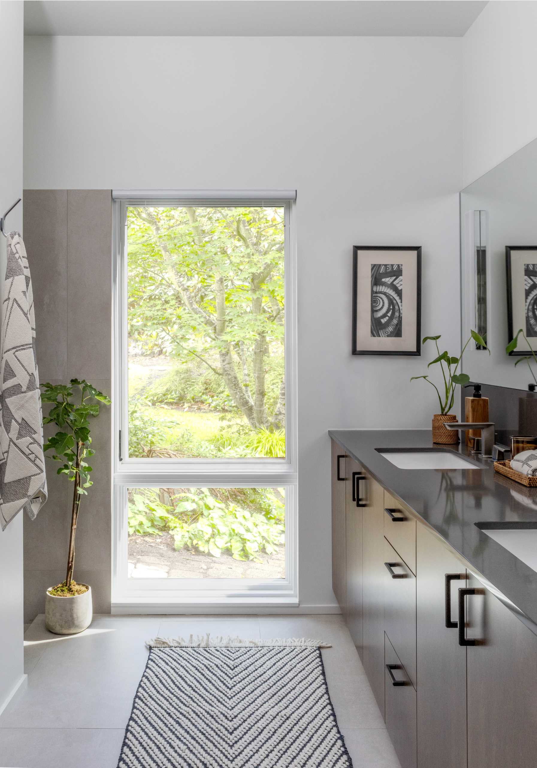 A modern bathroom with a double vanity and tall window.