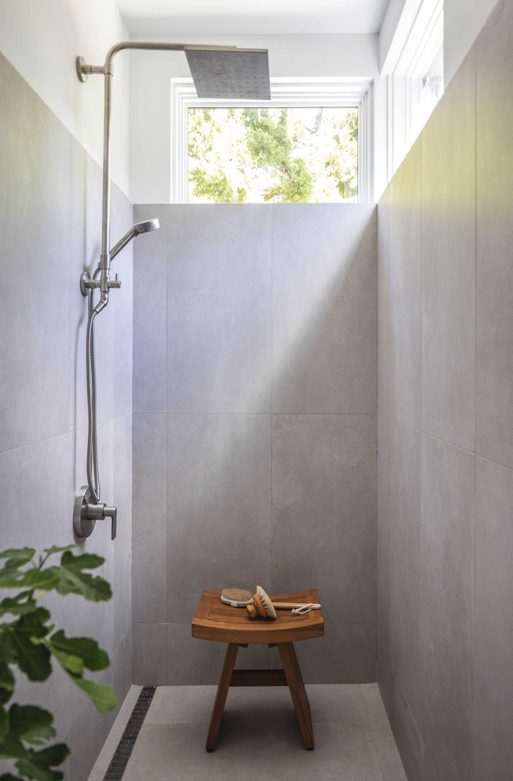 A modern shower with windows at the top of the wall.