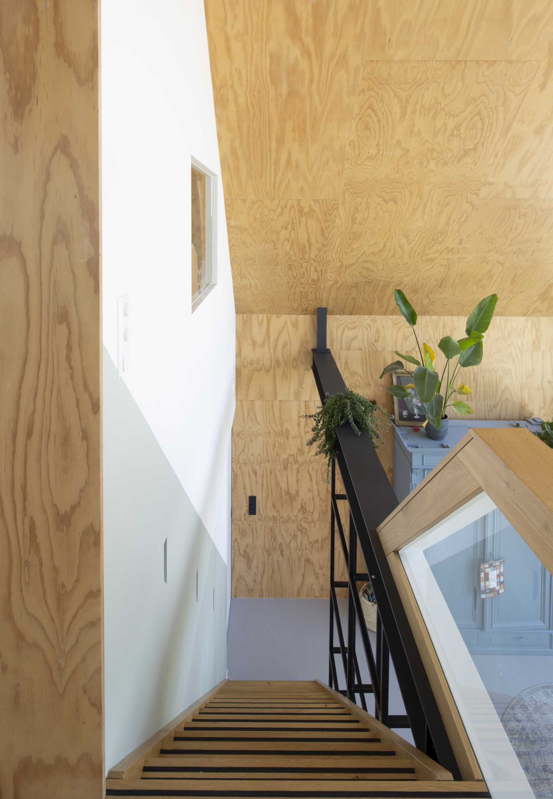 An open wooden staircase is supported by a steel rail, which also serves as a handrail, but can easily be converted into a bookcase due to its box shape.