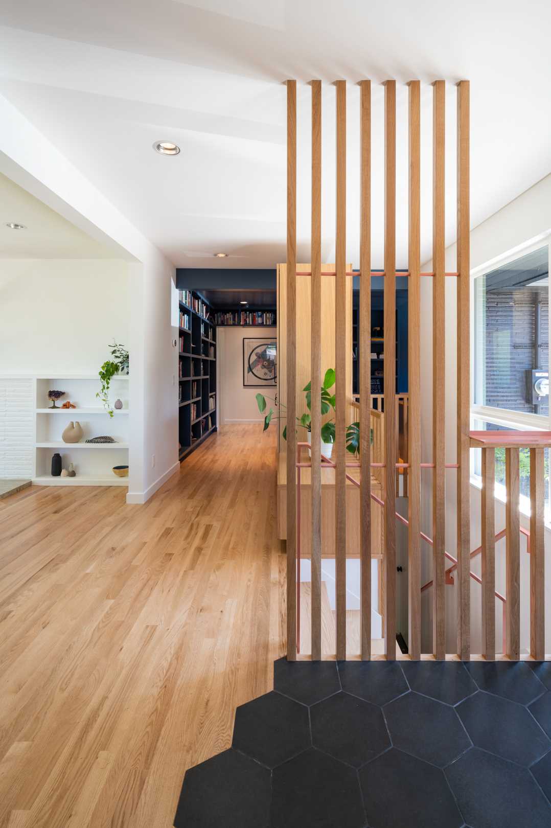 The remodeled basement stairs are now bright and open, with wood slat partitions and cabinetry helping to hide them.