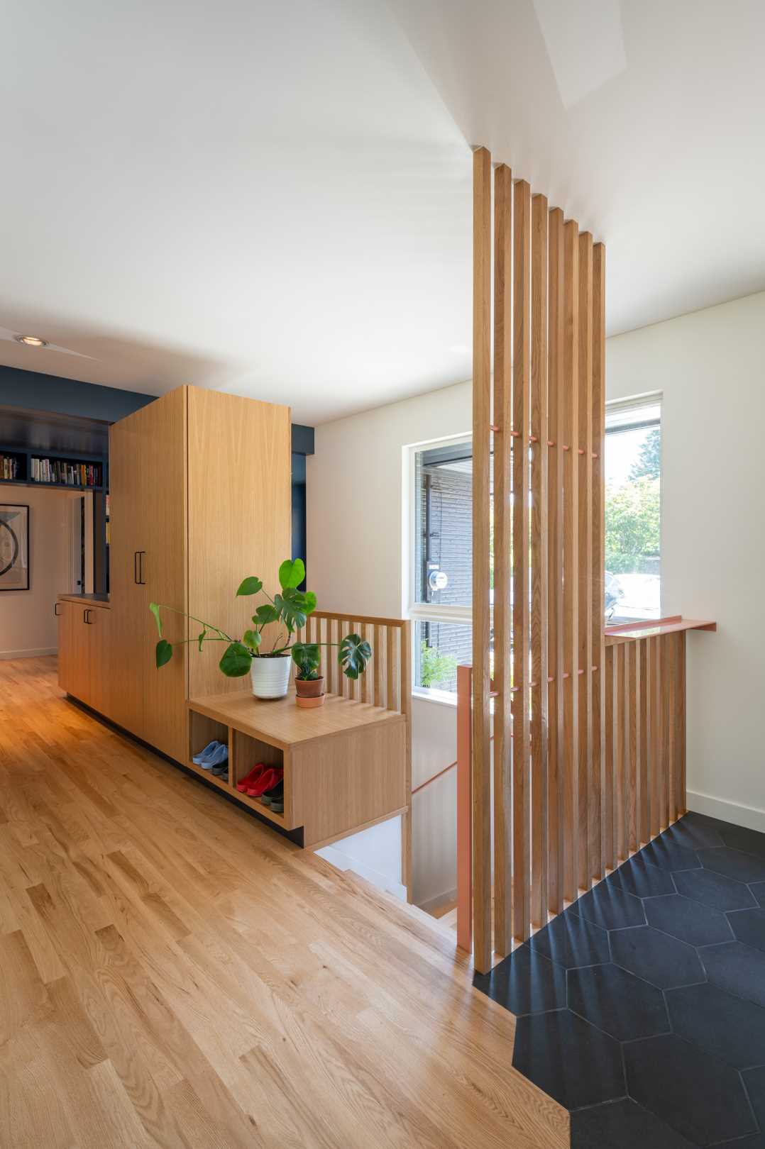 The remodeled basement stairs are now bright and open, with wood slat partitions and cabinetry helping to hide them.