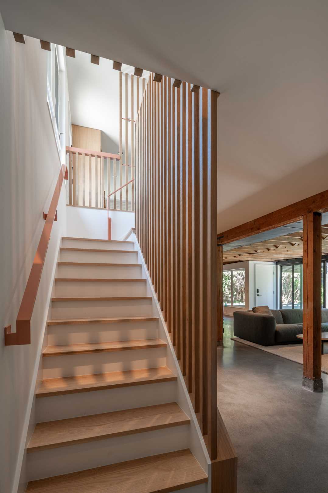 The remodeled basement stairs are now bright and open, with wood slat partitions and cabinetry helping to hide them.