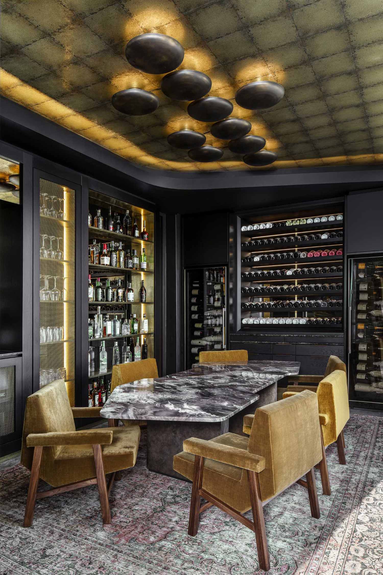 A modern wine room with a large table surrounded by chairs, and shelving for various bottle and gl، storage.
