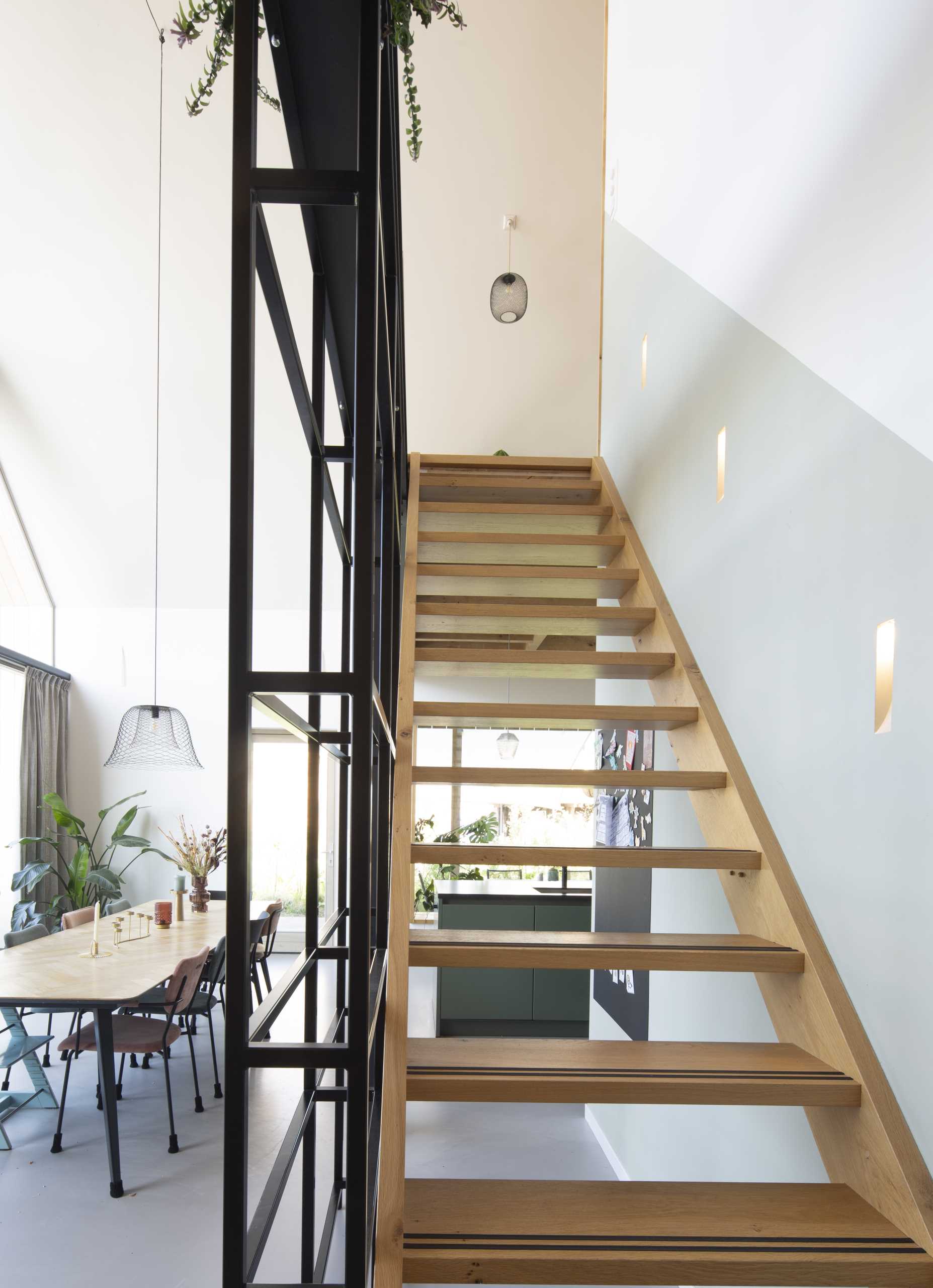 An open wooden staircase is supported by a steel rail, which also serves as a handrail, but can easily be converted into a bookcase due to its box shape.